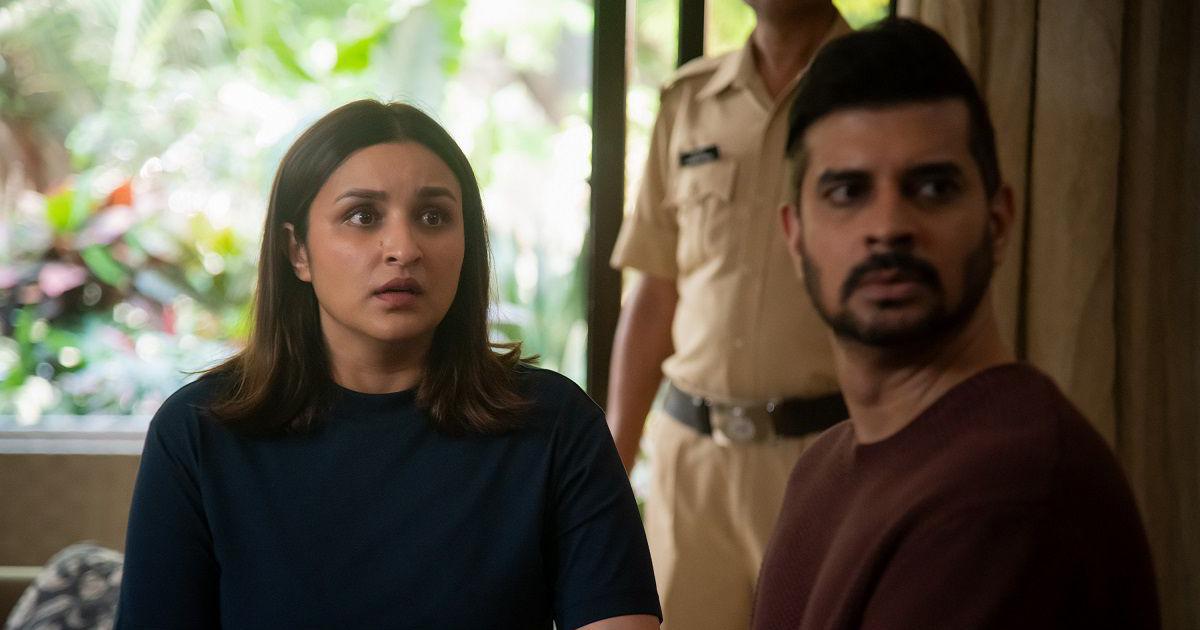 Parineeti Chopra as Anvita and Tahir Raj Bhasin as Alok look towards someone in a police station, with a uniformed officer behind them.