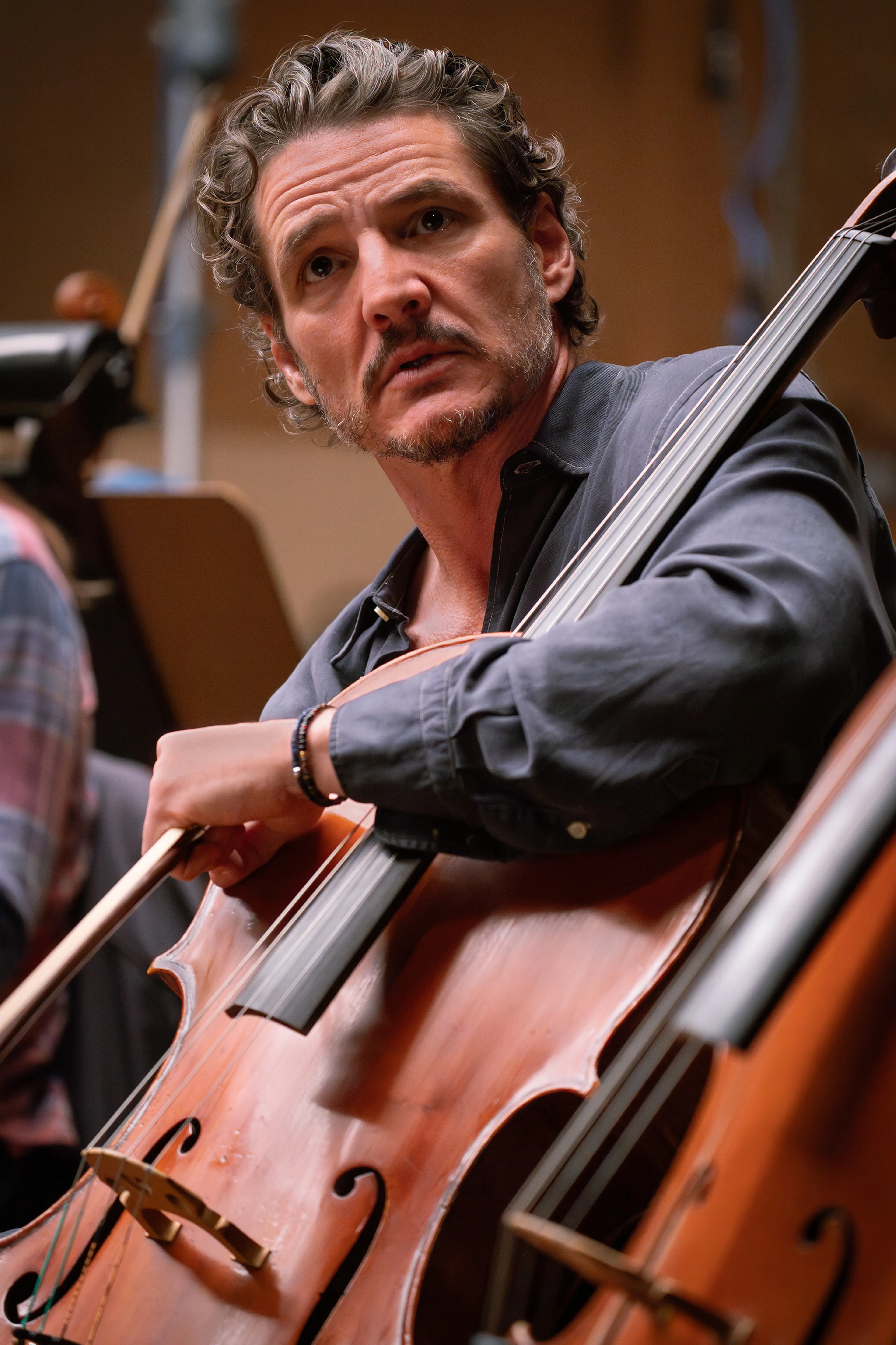 Pedro Pascal holds a cello and bow as Alex Serian in Behemoth!.