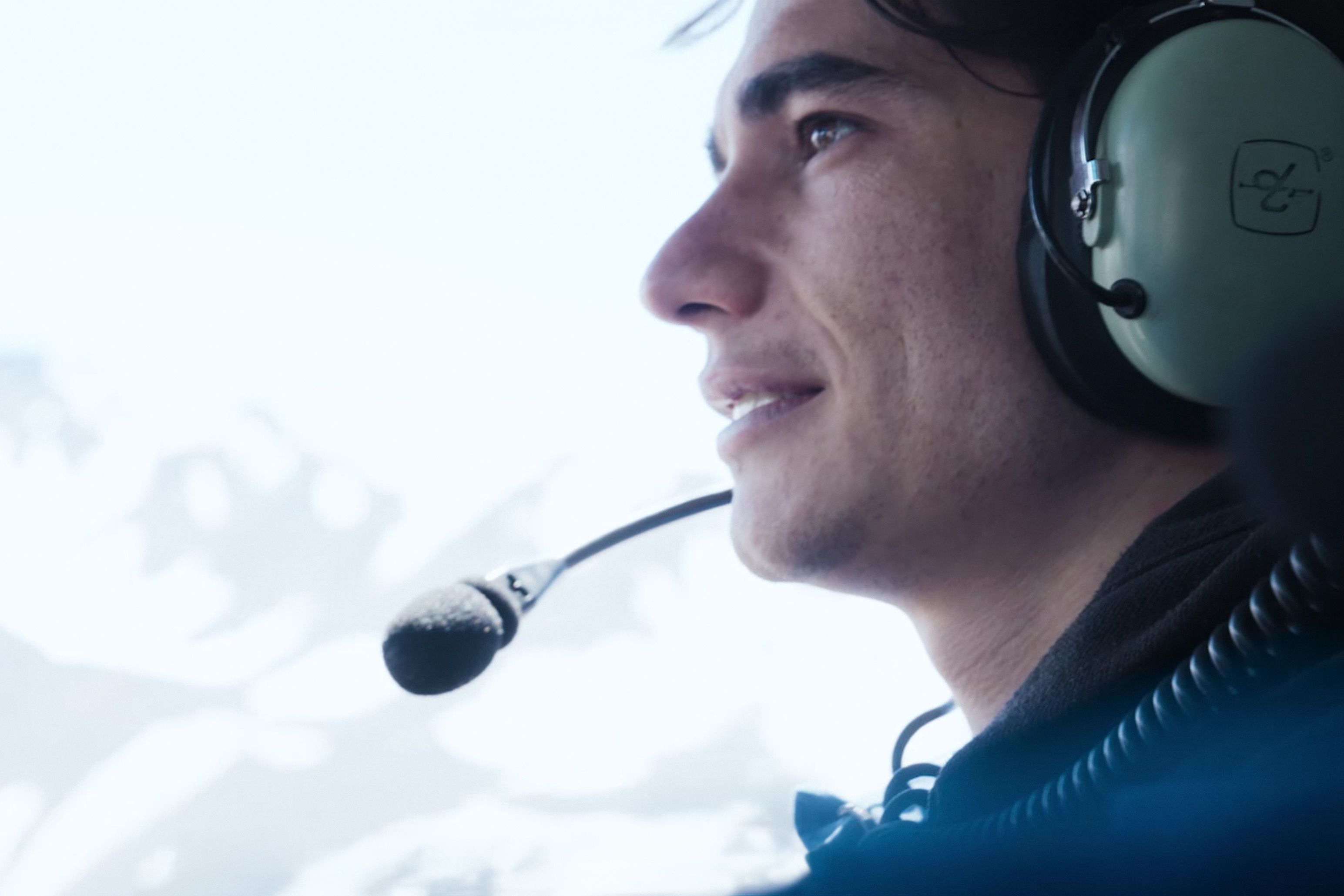 A participant wearing an aviation headset looks out from an aircraft in an official Beyond Society still.