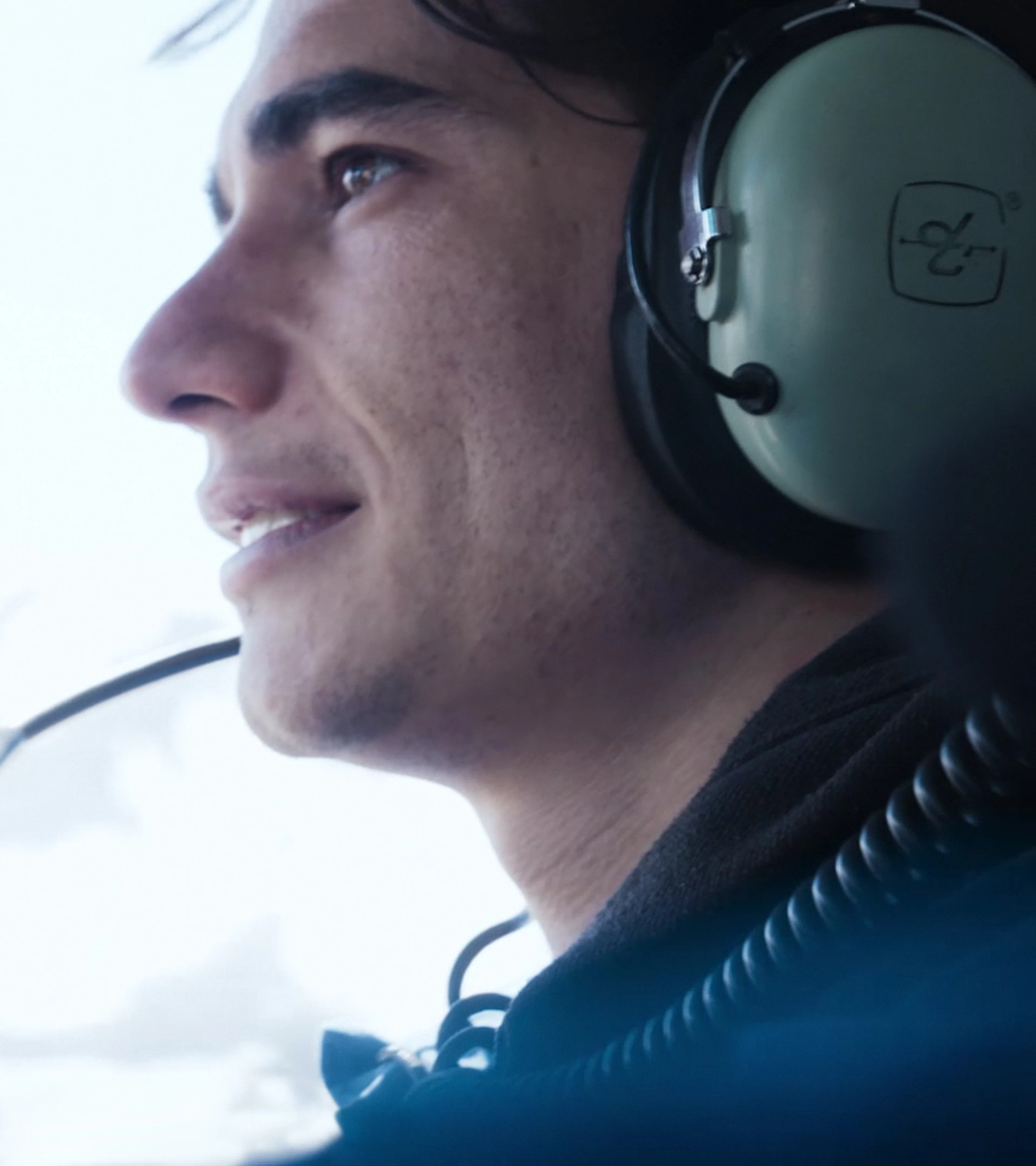 A participant wearing an aviation headset looks out from an aircraft in an official Beyond Society still.