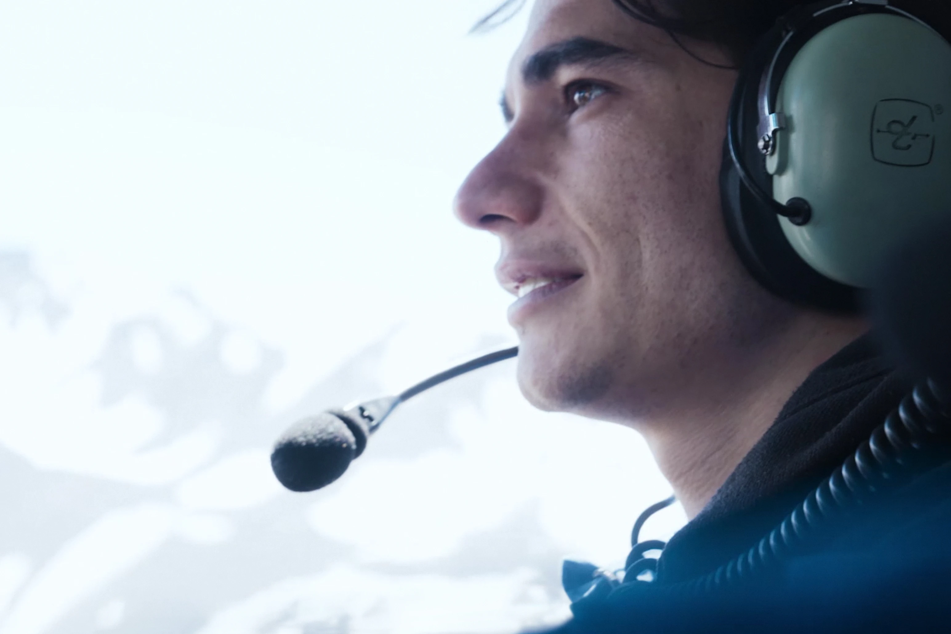 A participant wearing an aviation headset looks out from an aircraft in an official Beyond Society still.