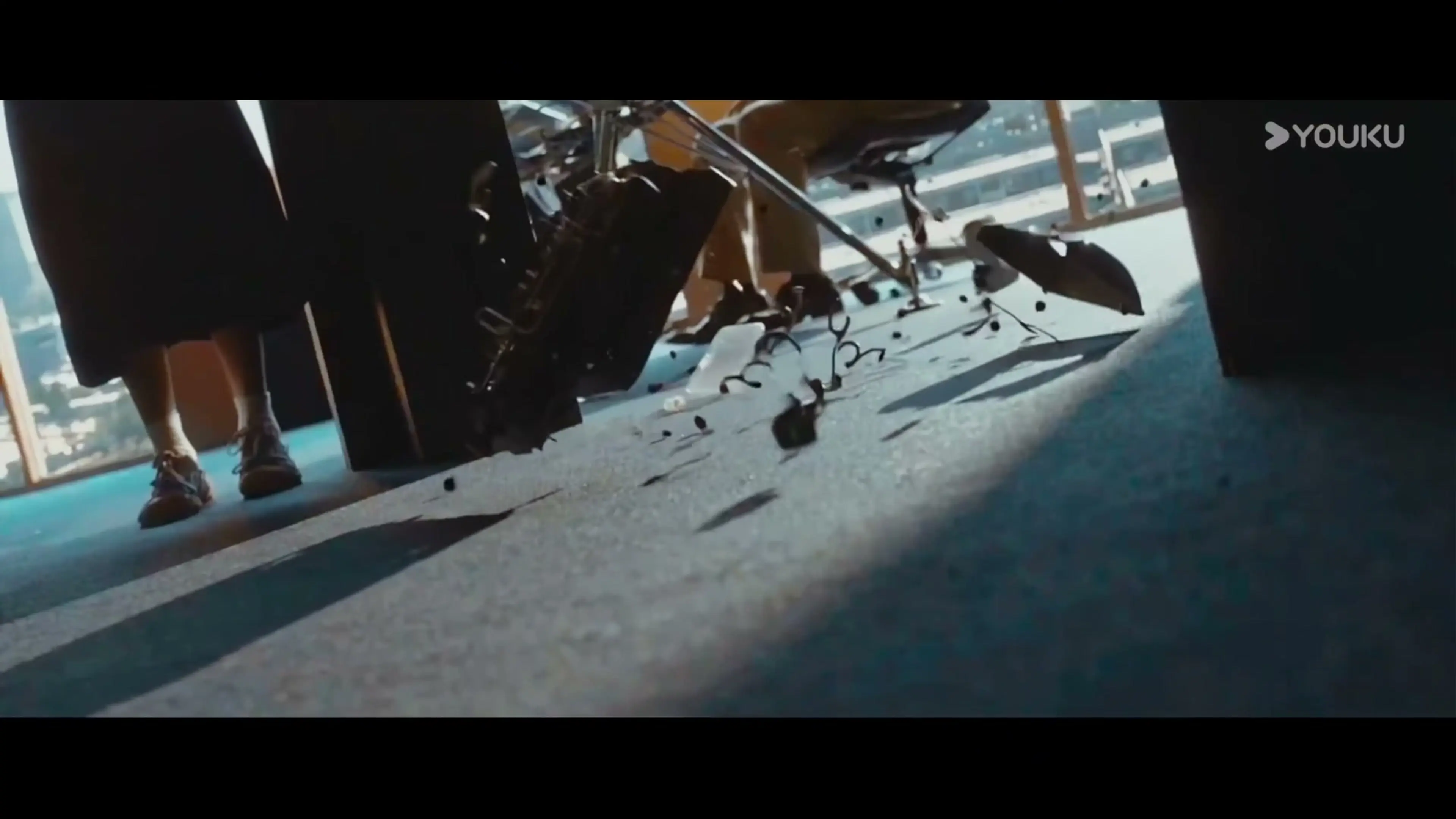 An antique typewriter falls beside an office desk, with pieces scattering above the floor.