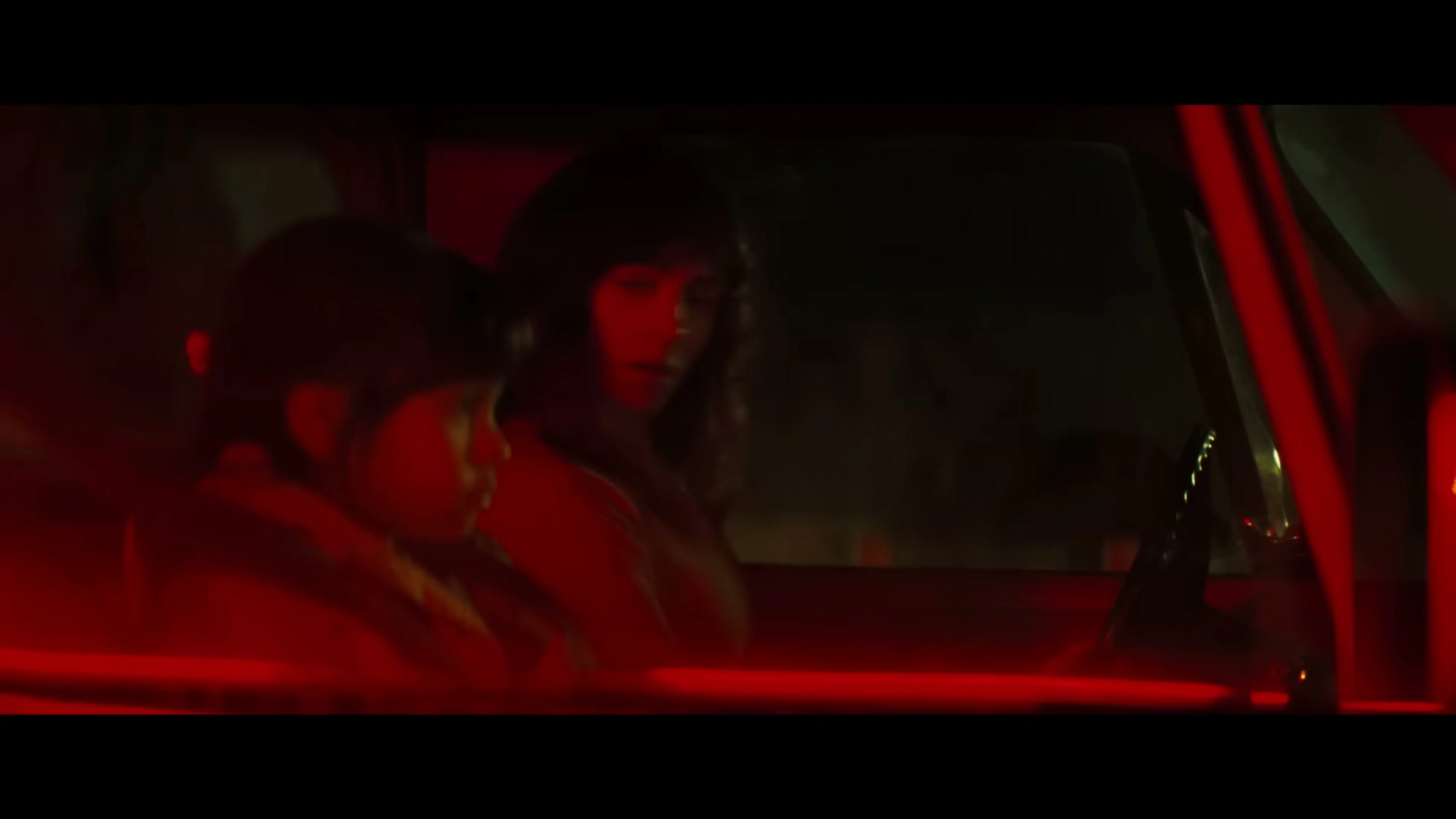 Celeste sits beside her daughter Daisy inside a red-lit vehicle in Onslaught.