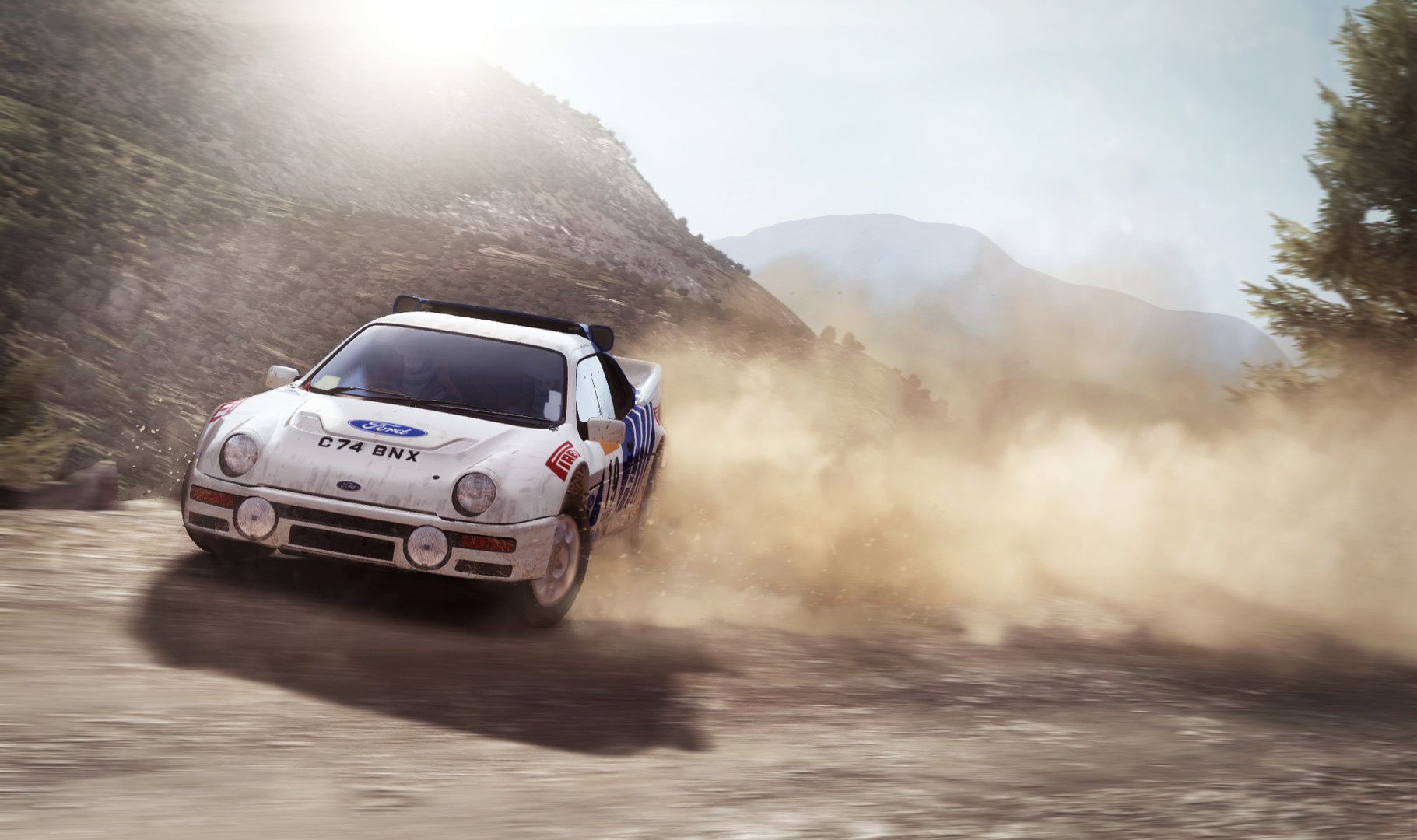 White rally car kicks up a large dust cloud on a dry mountain track.