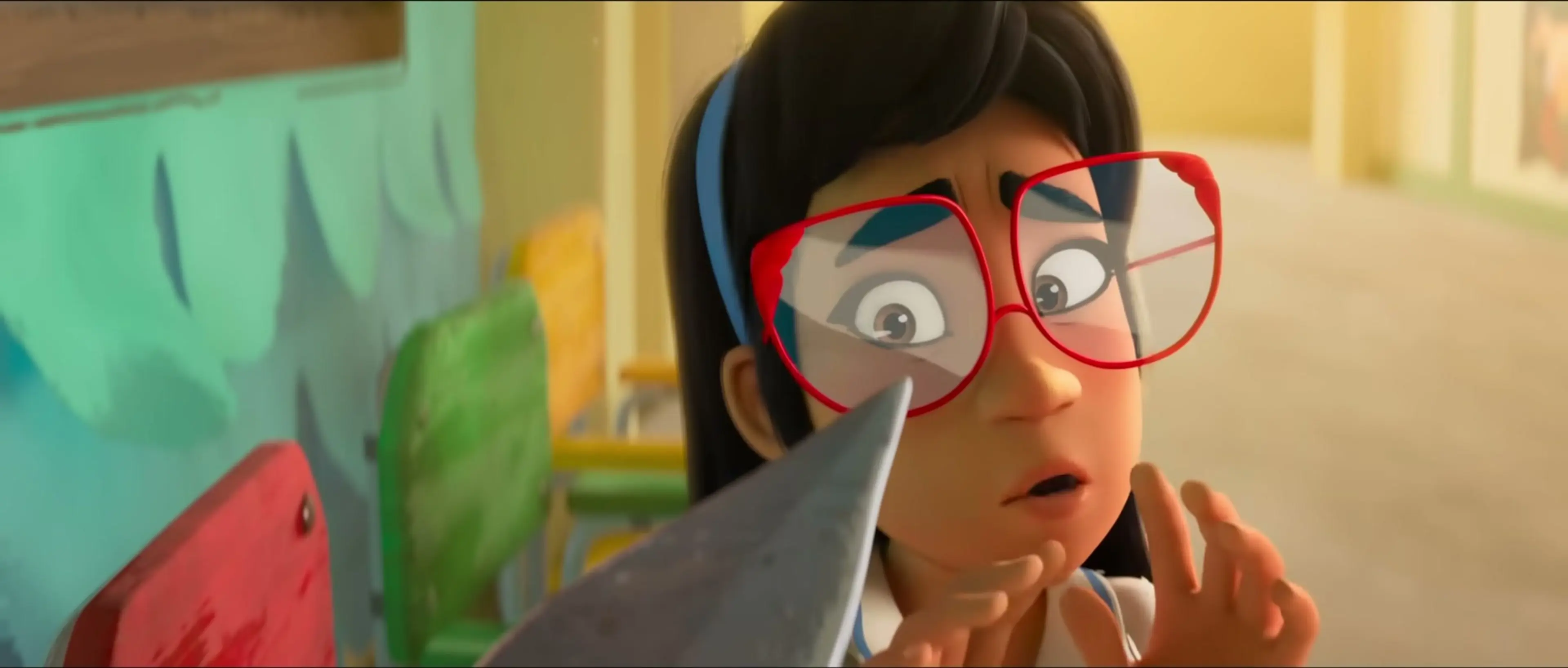 A younger Raissa wears large red glasses and raises her hands beside a pointed object.