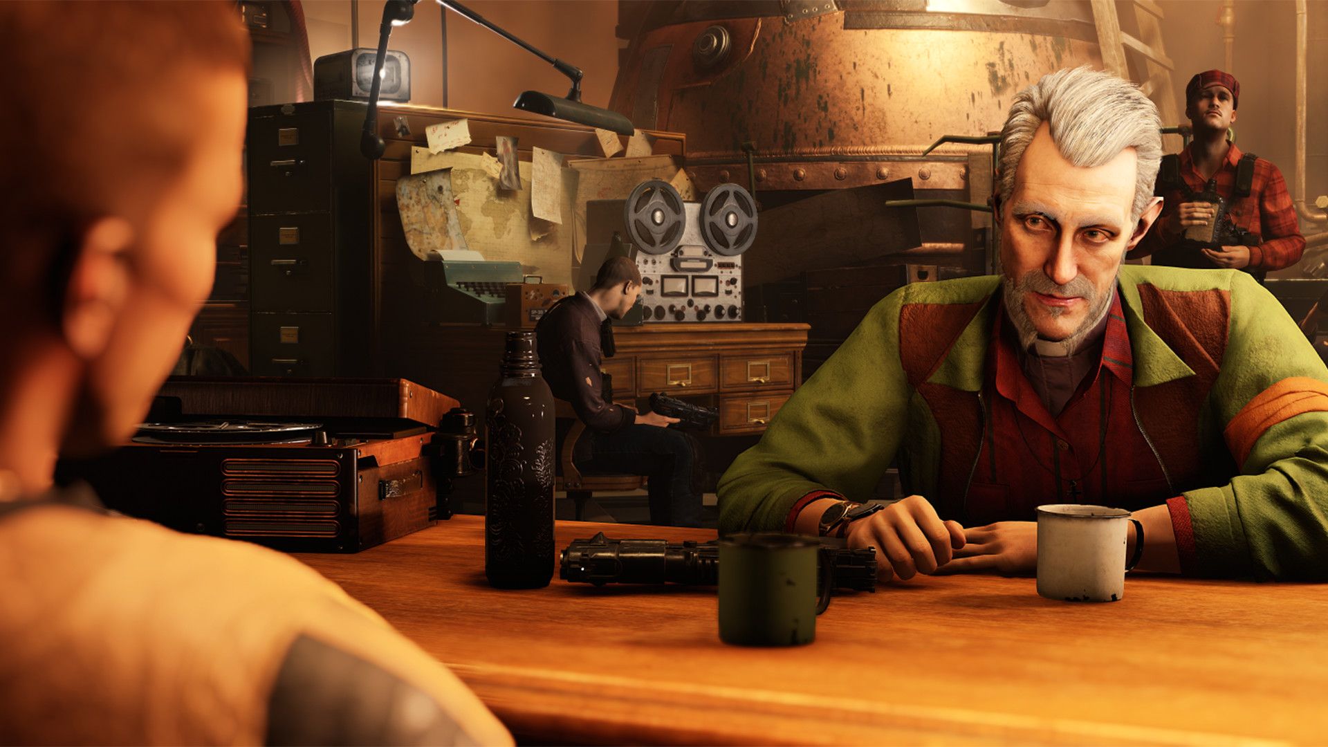 A gray-haired man speaks across a table, with radios, tools and other characters behind him.
