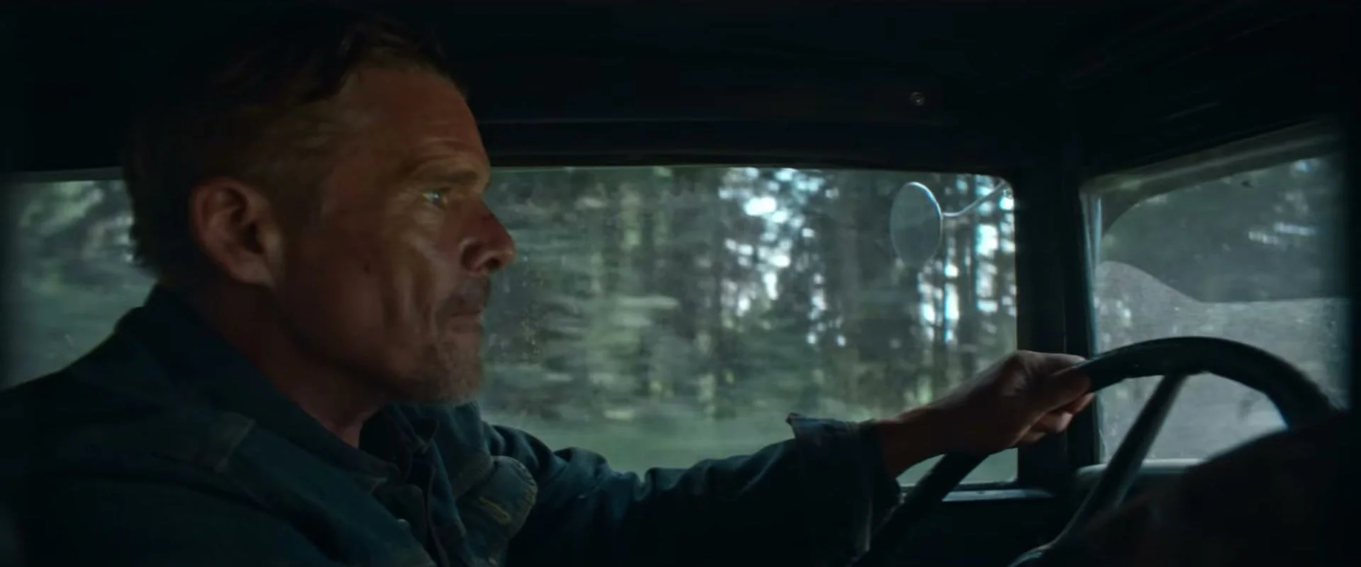 Ethan Hawke drives a vehicle through the woods in The Weight.