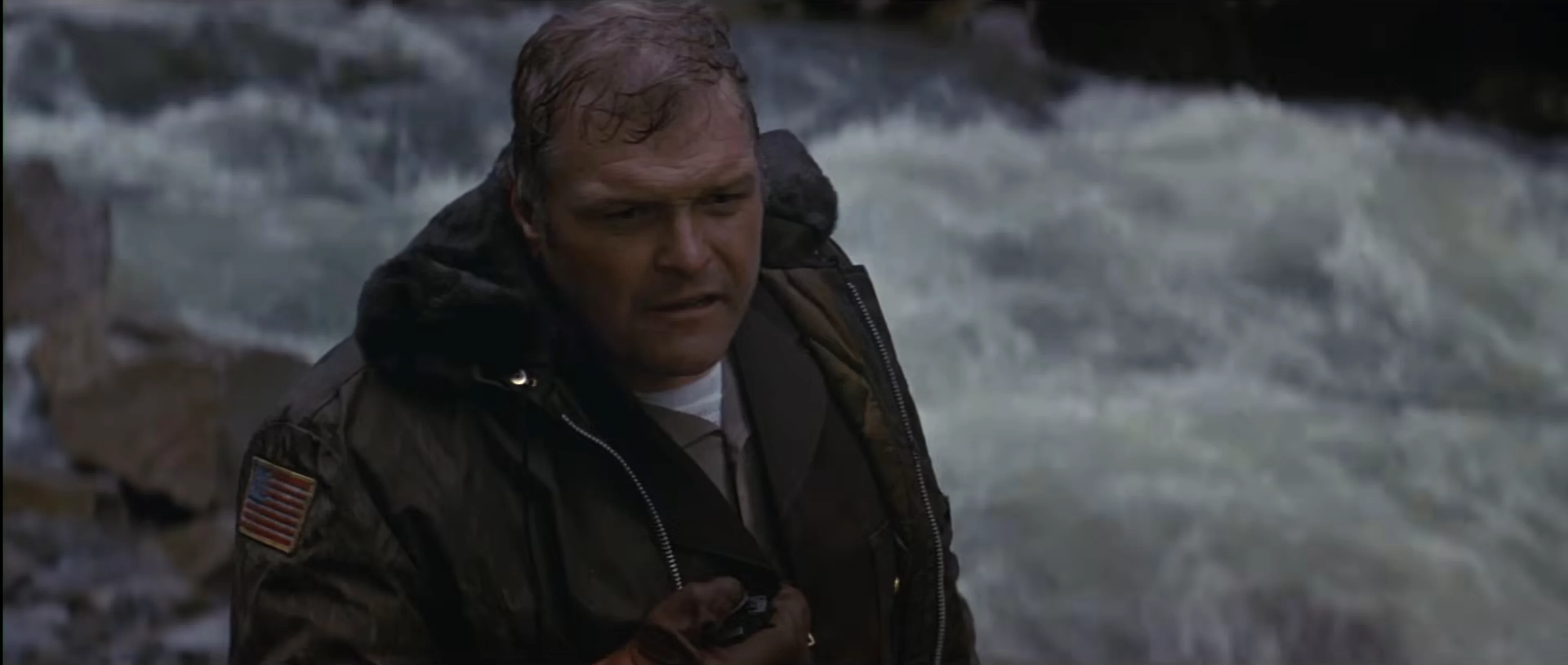 A uniformed officer struggles in rushing river water during the pursuit in First Blood.