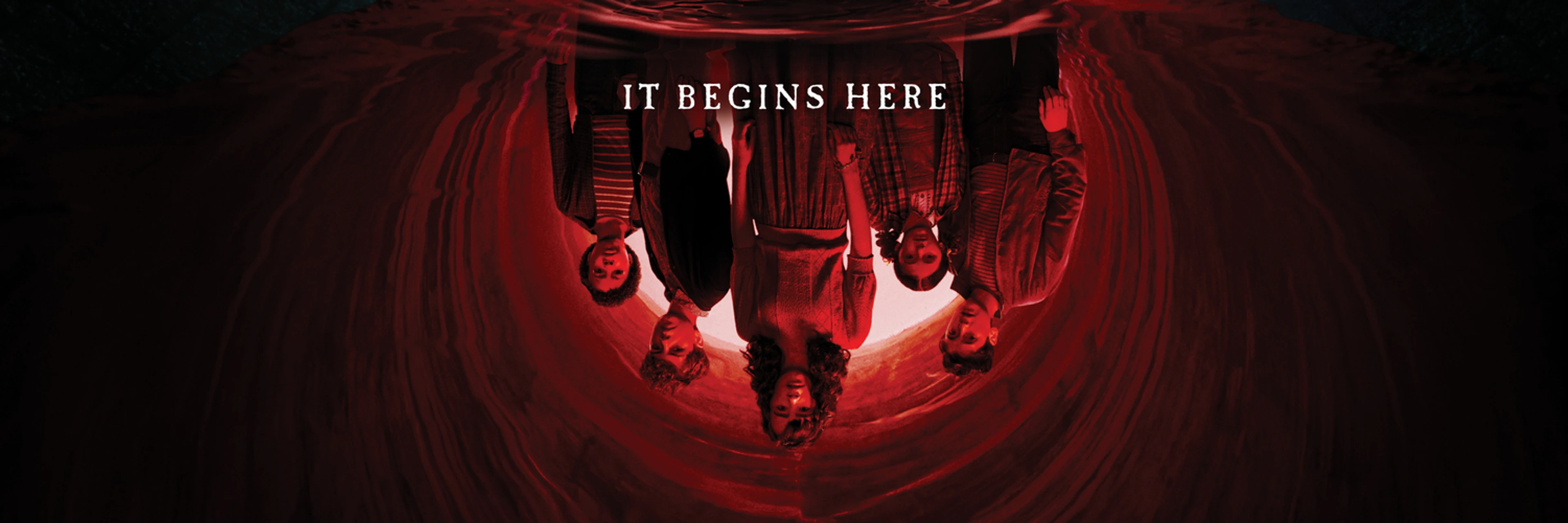 The cast of IT: Welcome to Derry hangs upside down in a red tunnel as Pennywise watches from below.