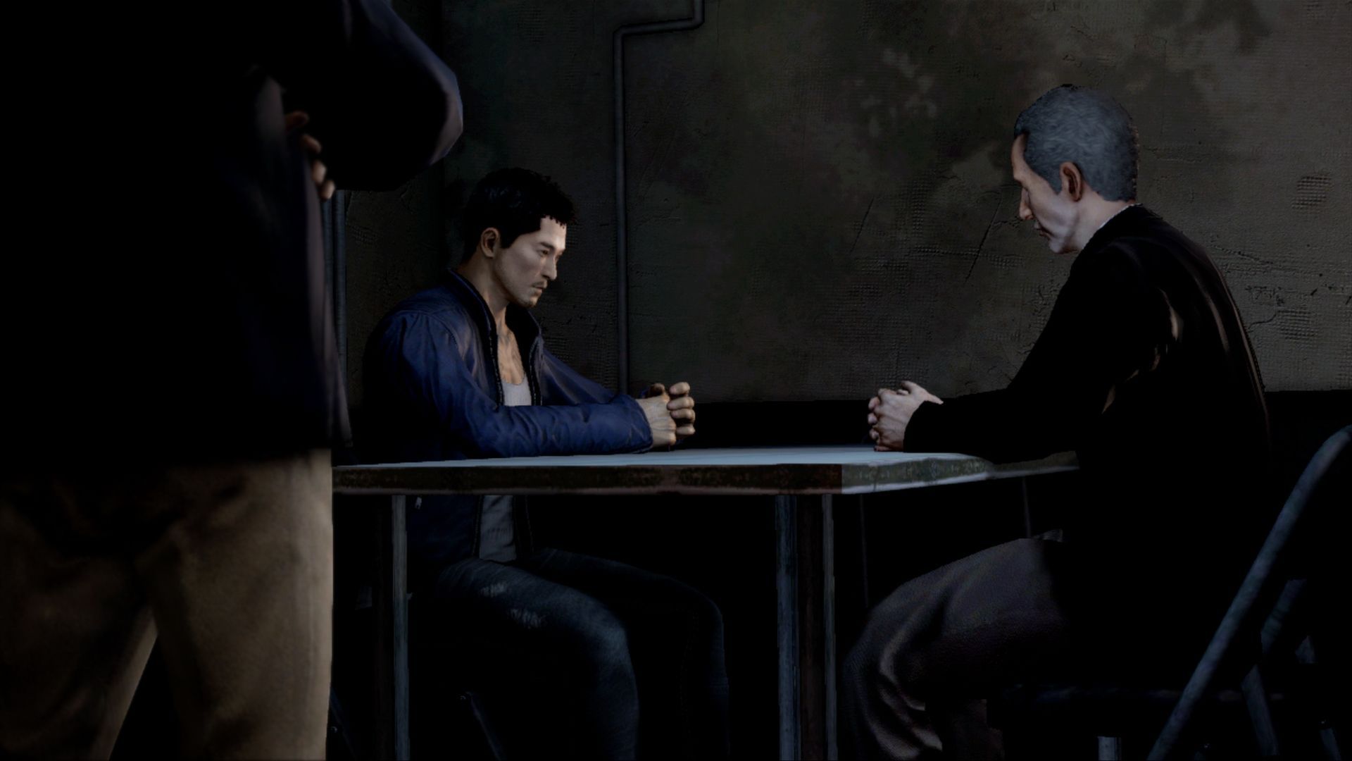Wei sits across a table from an older man in a dim room.