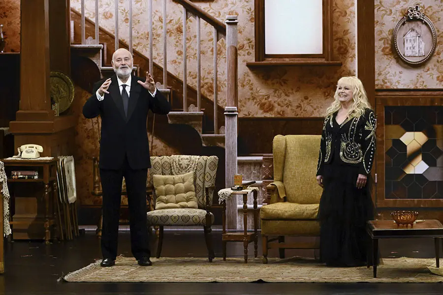 Rob Reiner and Sally Struthers stand on a recreated All in the Family set at the 75th Emmy Awards.