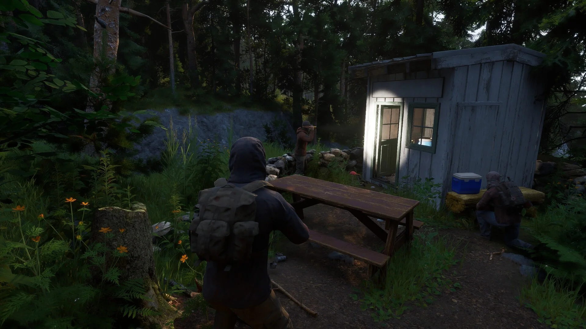 Three survivors move through a forest near a small cabin in Ardem.
