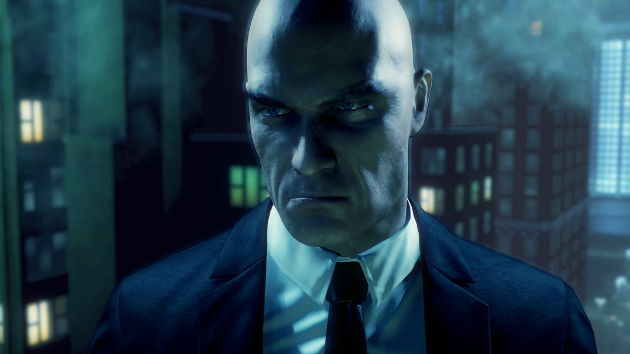Close view of Agent 47 in a black suit against city buildings at night.