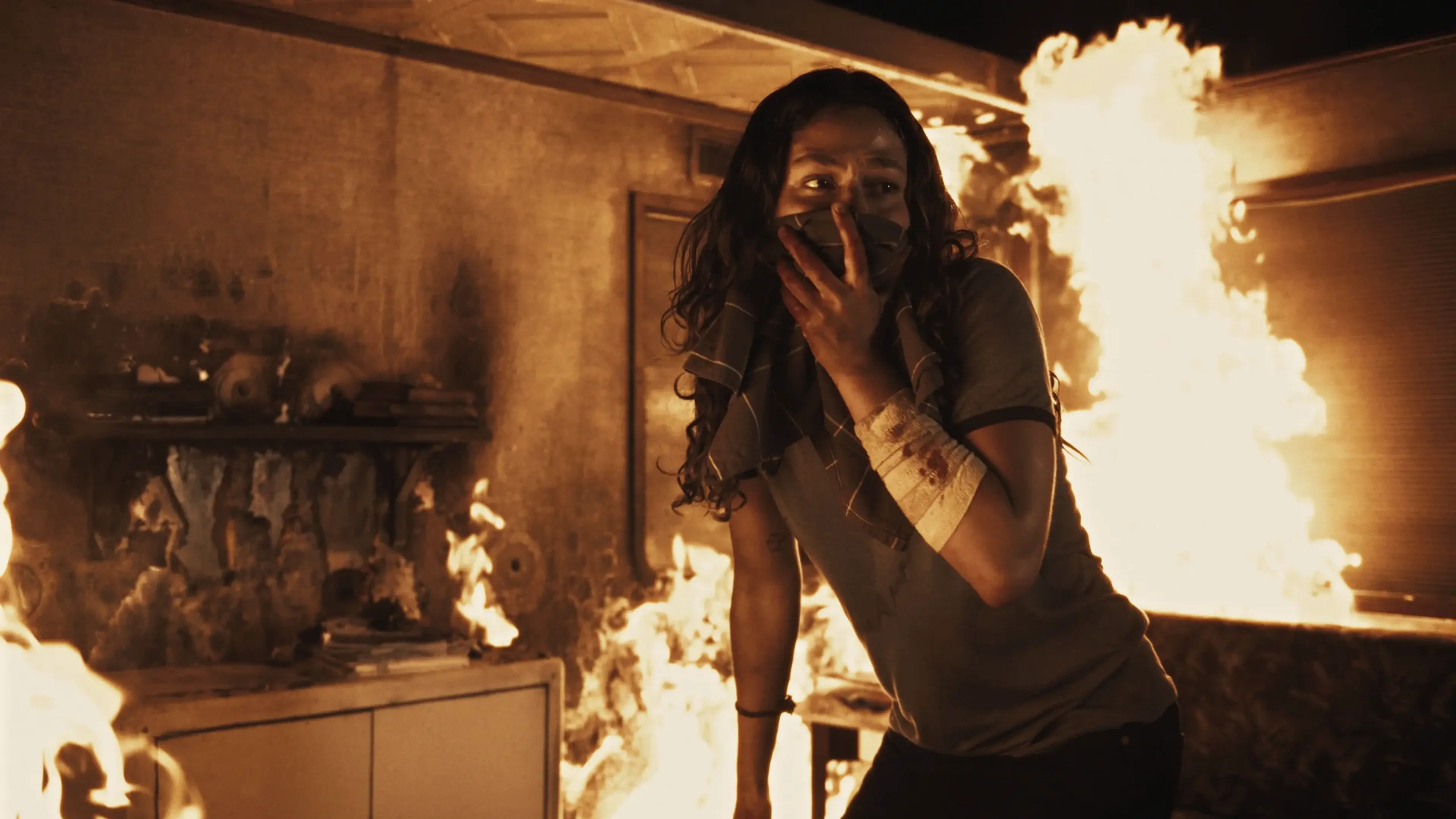 Phoebe covers her mouth while escaping a room engulfed in flames in City of Blood.