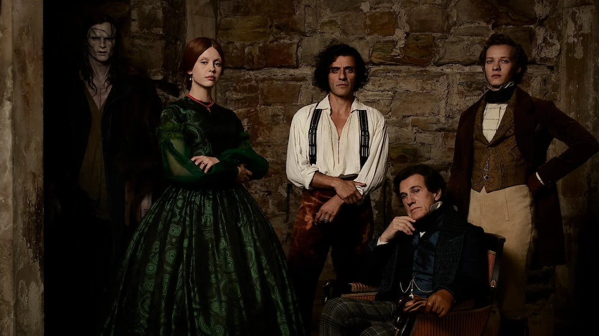 Mia Goth stands alongside her Frankenstein co-stars in a stone-walled set portrait.