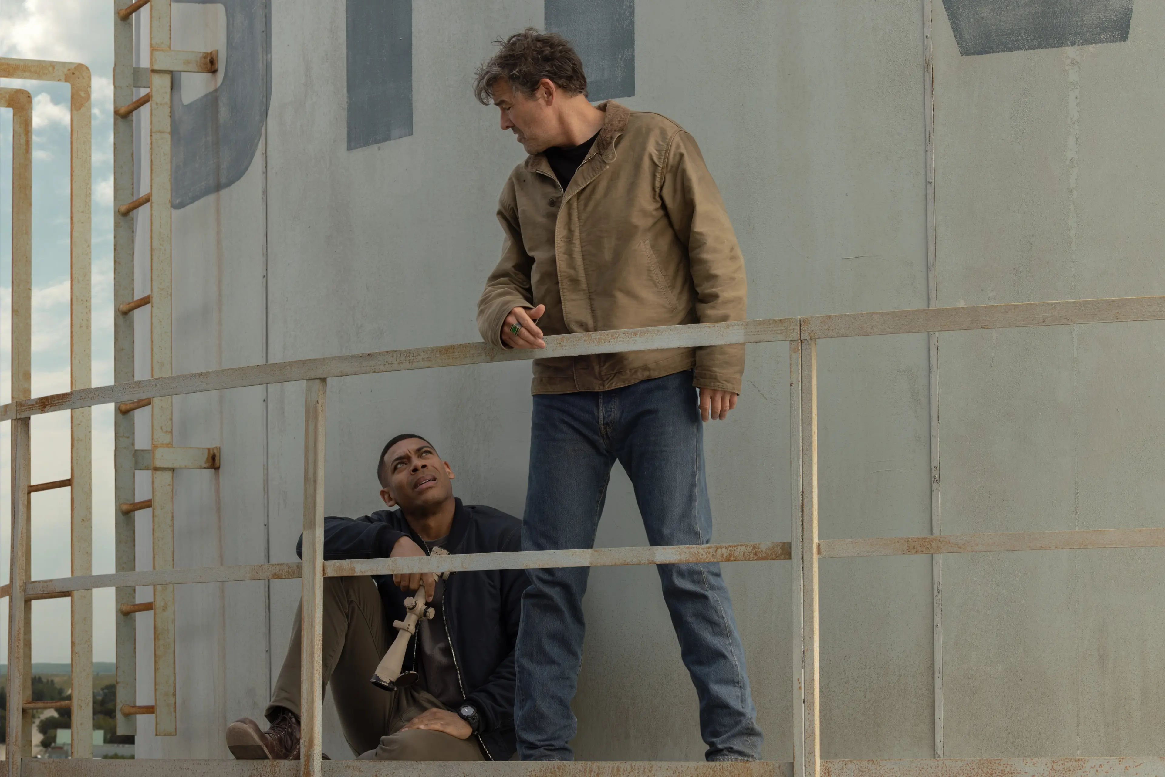 Kyle Chandler as Hal Jordan stands above Aaron Pierre as John Stewart at a tower in Lanterns.