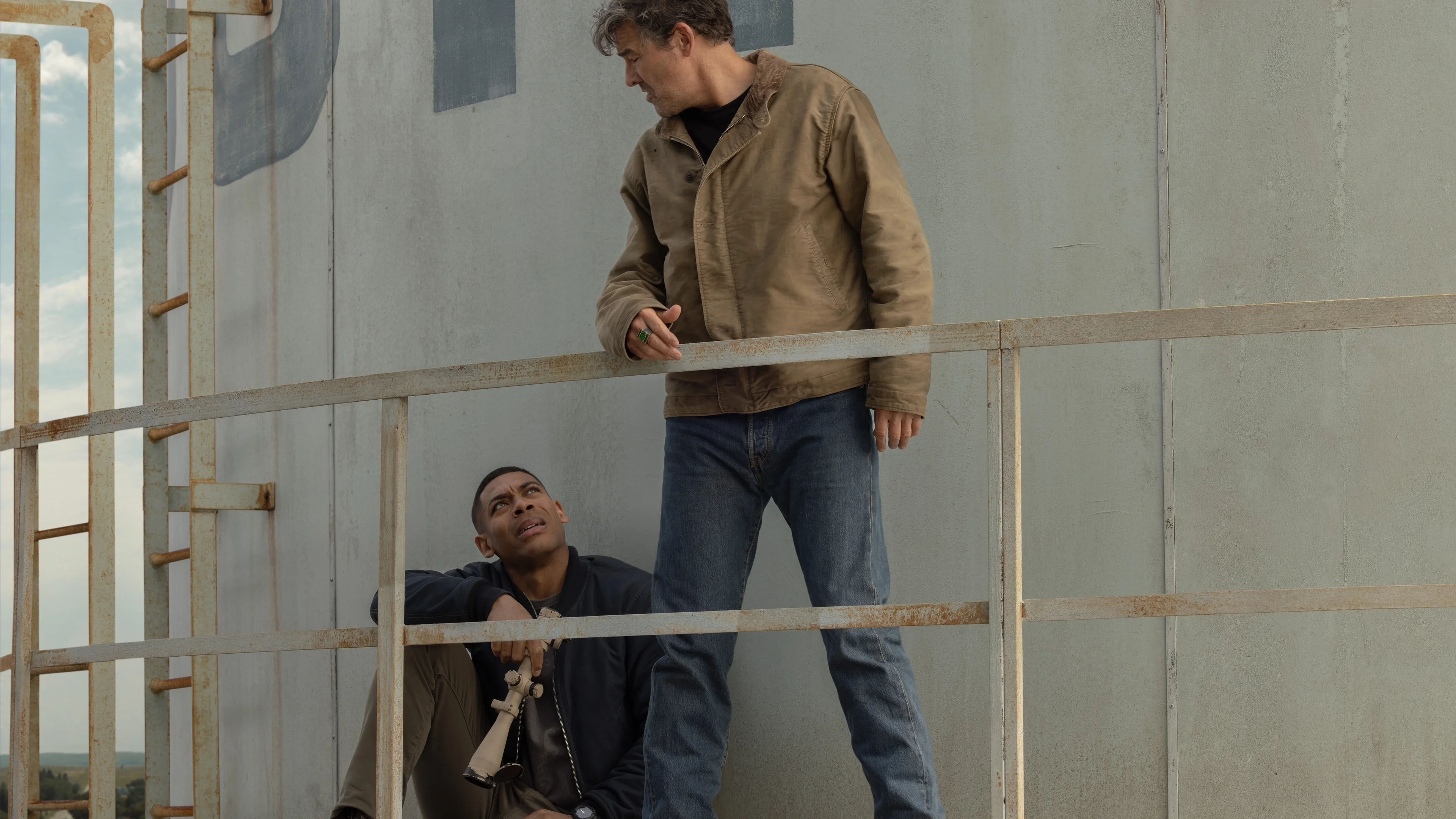 Kyle Chandler as Hal Jordan stands above Aaron Pierre as John Stewart at a tower in Lanterns.