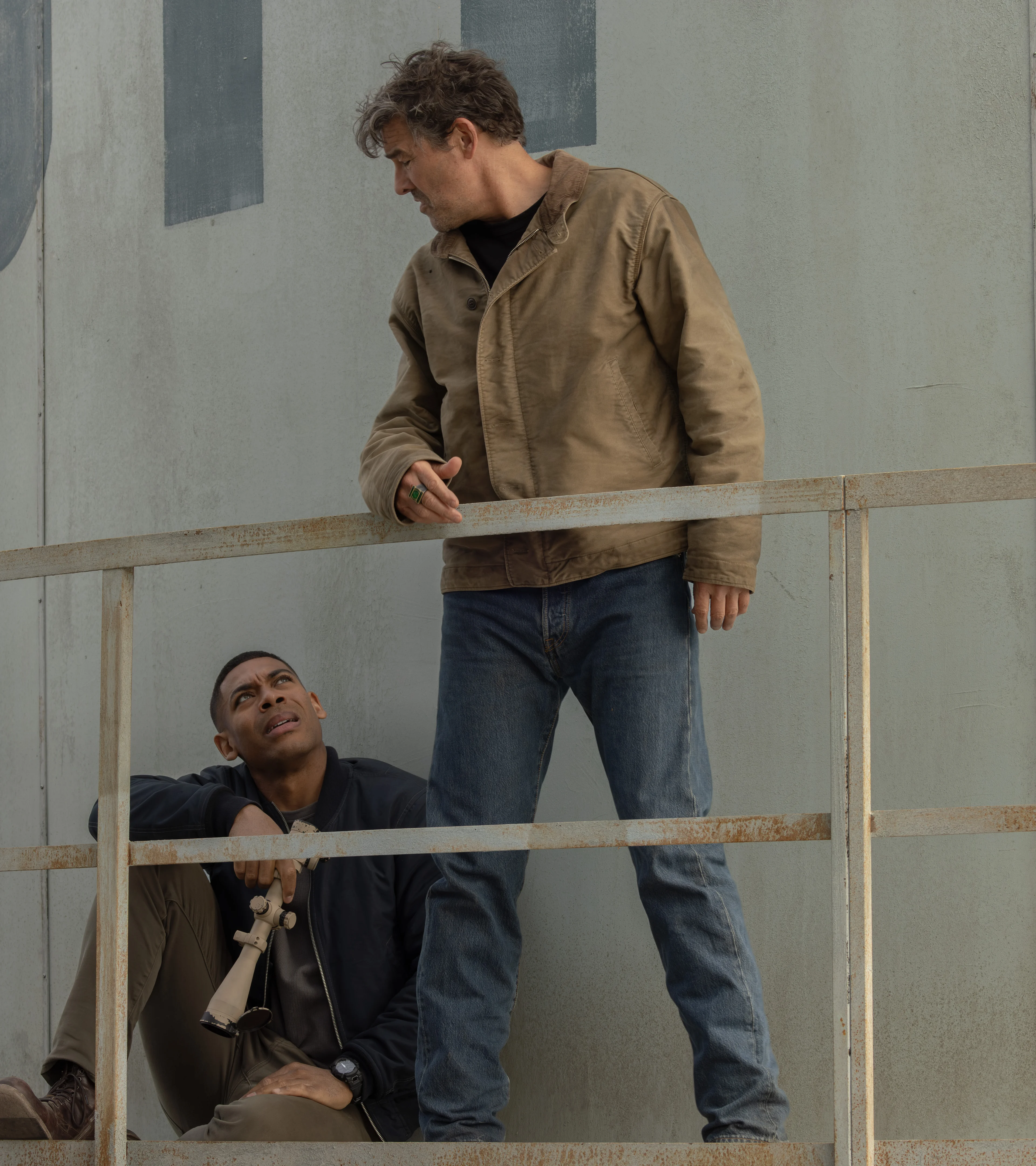 Kyle Chandler as Hal Jordan stands above Aaron Pierre as John Stewart at a tower in Lanterns.