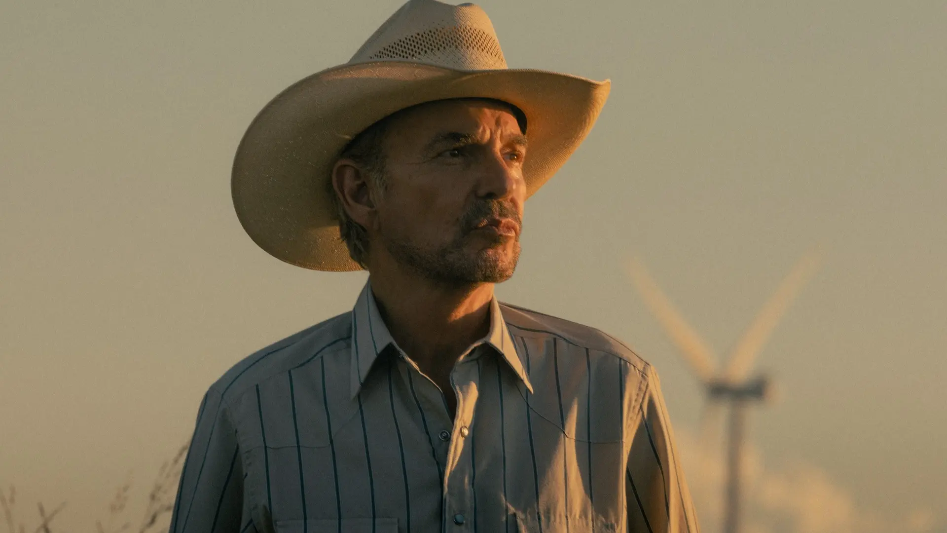 Billy Bob Thornton as Tommy Norris stands outdoors in warm evening light in Landman.