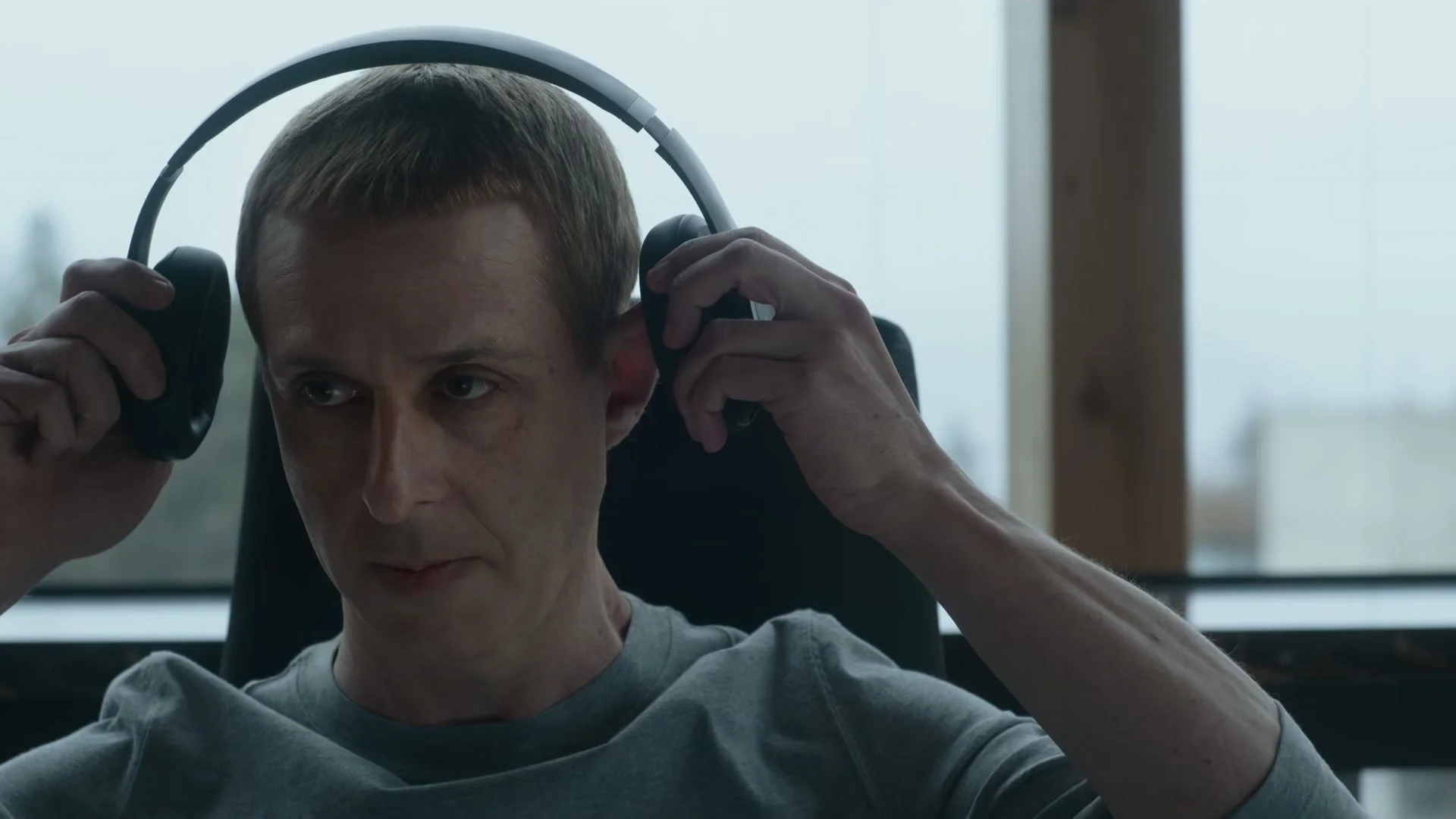 Jeremy Strong places headphones over his ears as Mark Zuckerberg in The Social Reckoning.