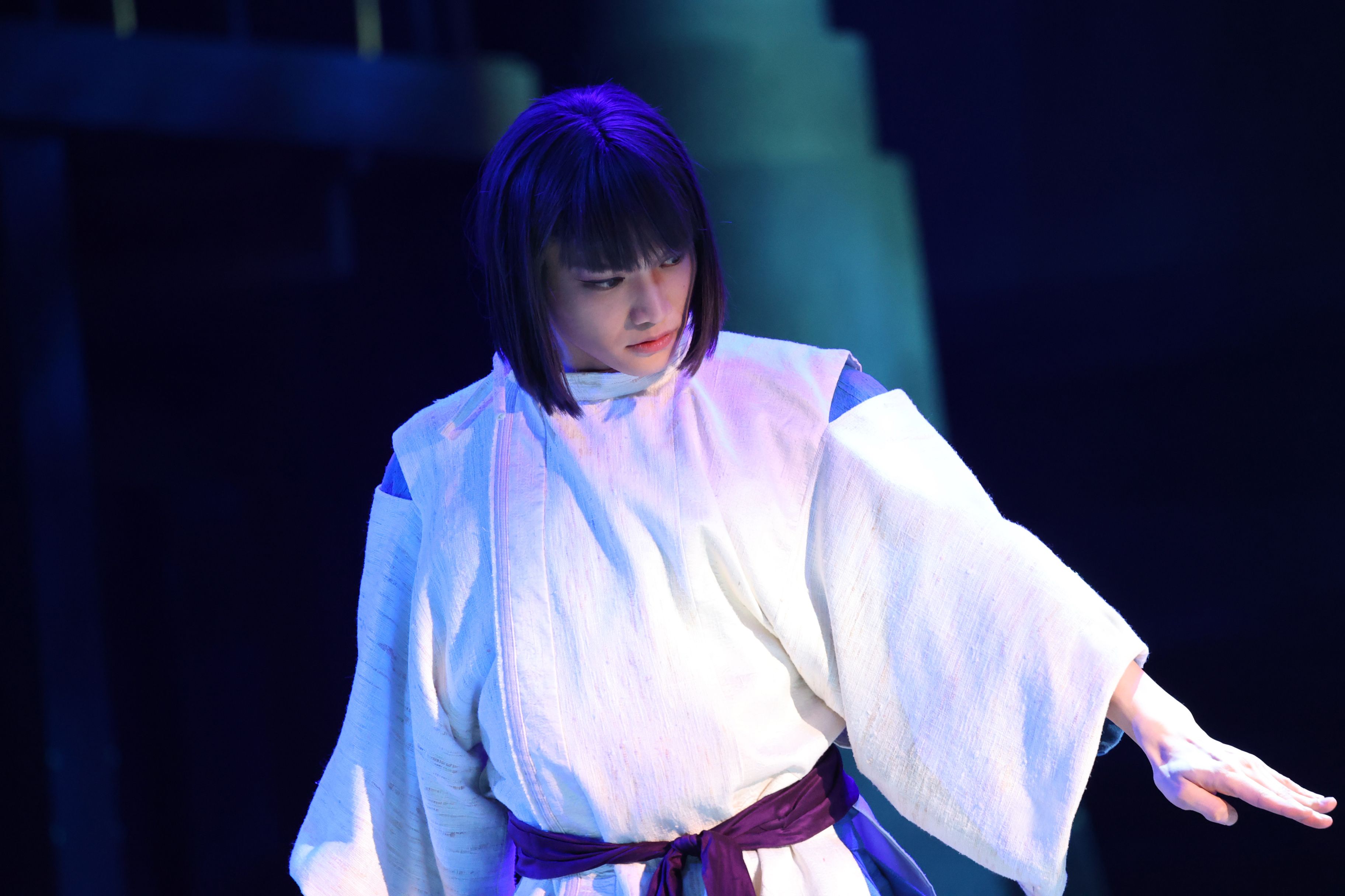 Hiroki Miura as Haku stands beneath blue stage lighting in Spirited Away: Live on Stage.
