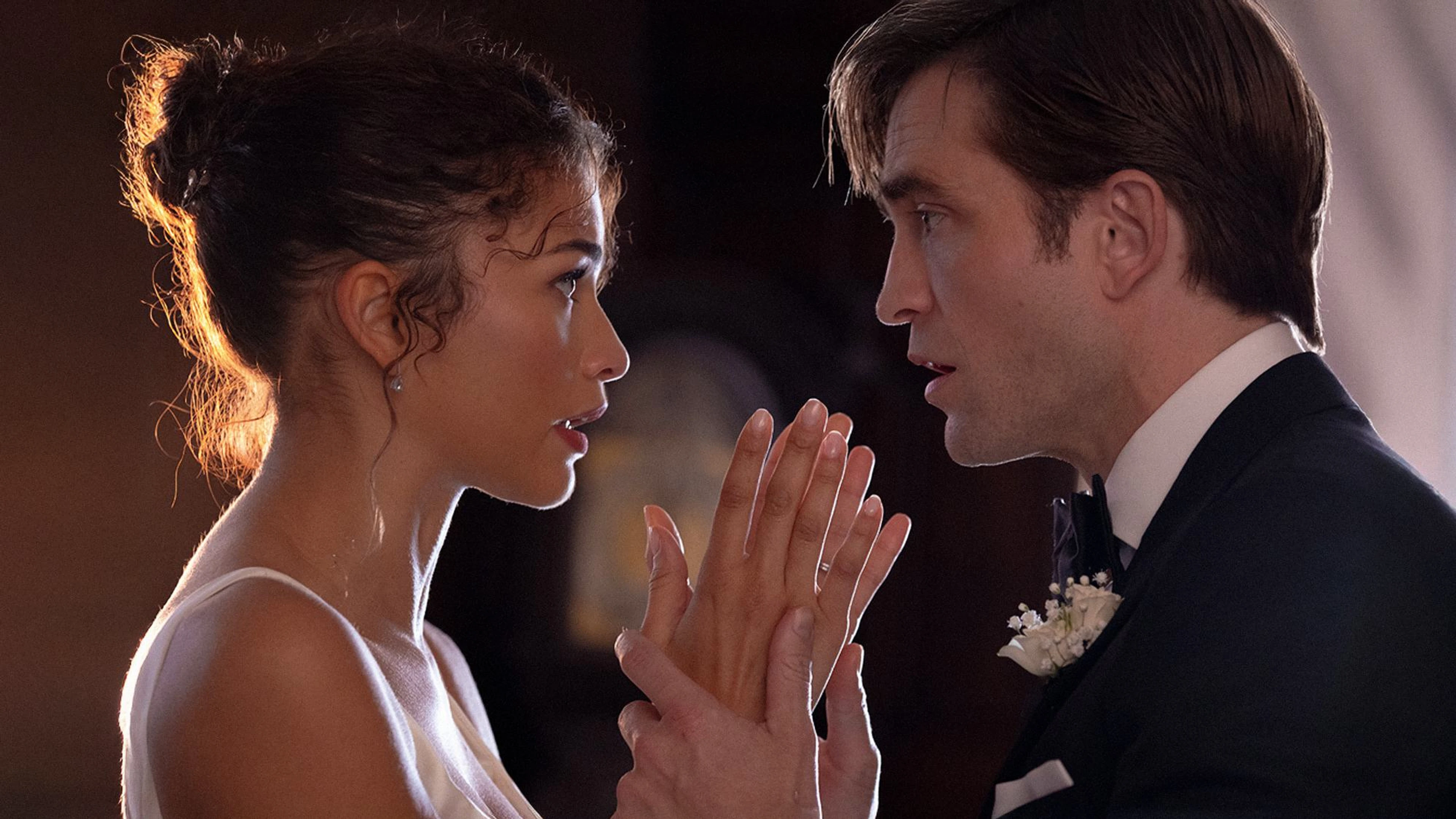 Emma and Charlie face each other in wedding clothes with their hands raised between them.