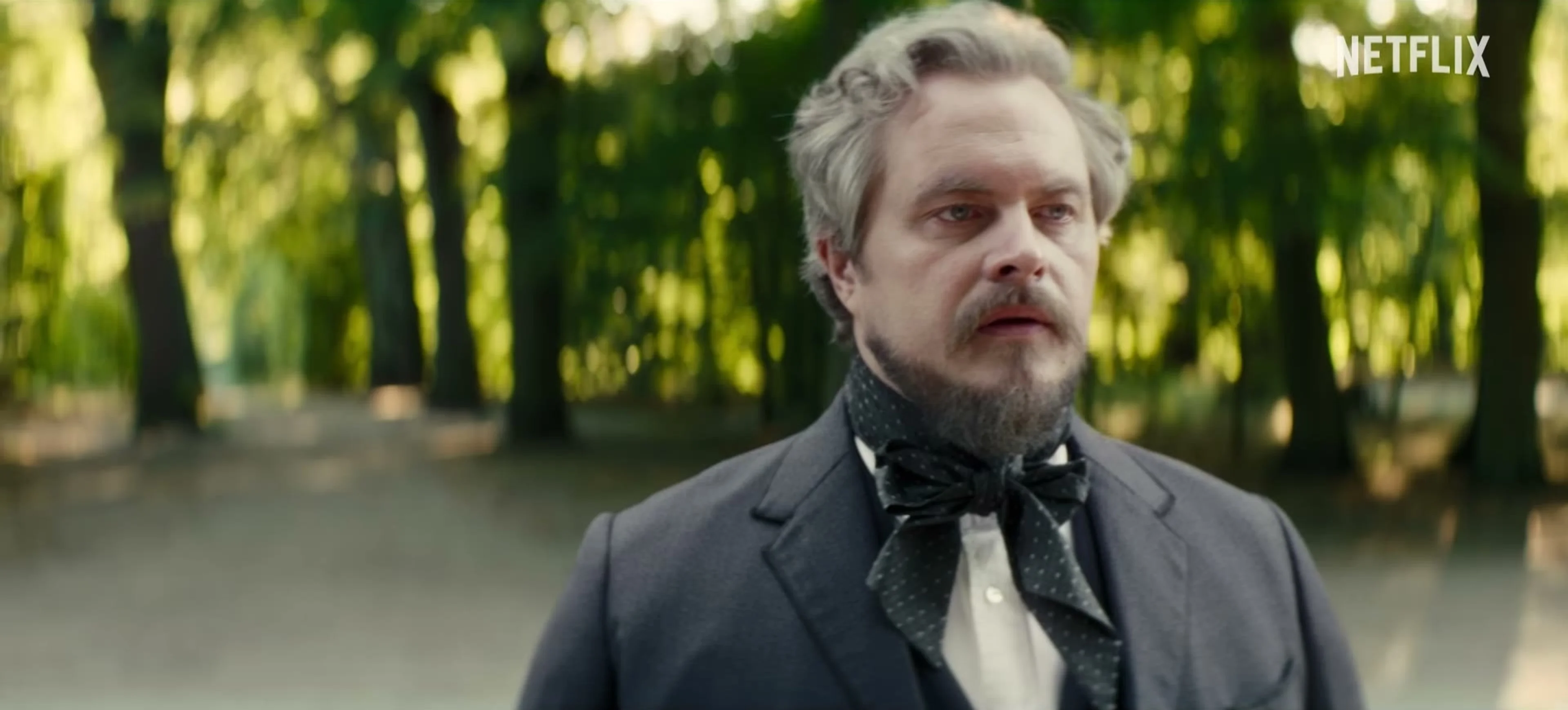 Stanisław Wokulski stands outdoors in nineteenth-century clothing.