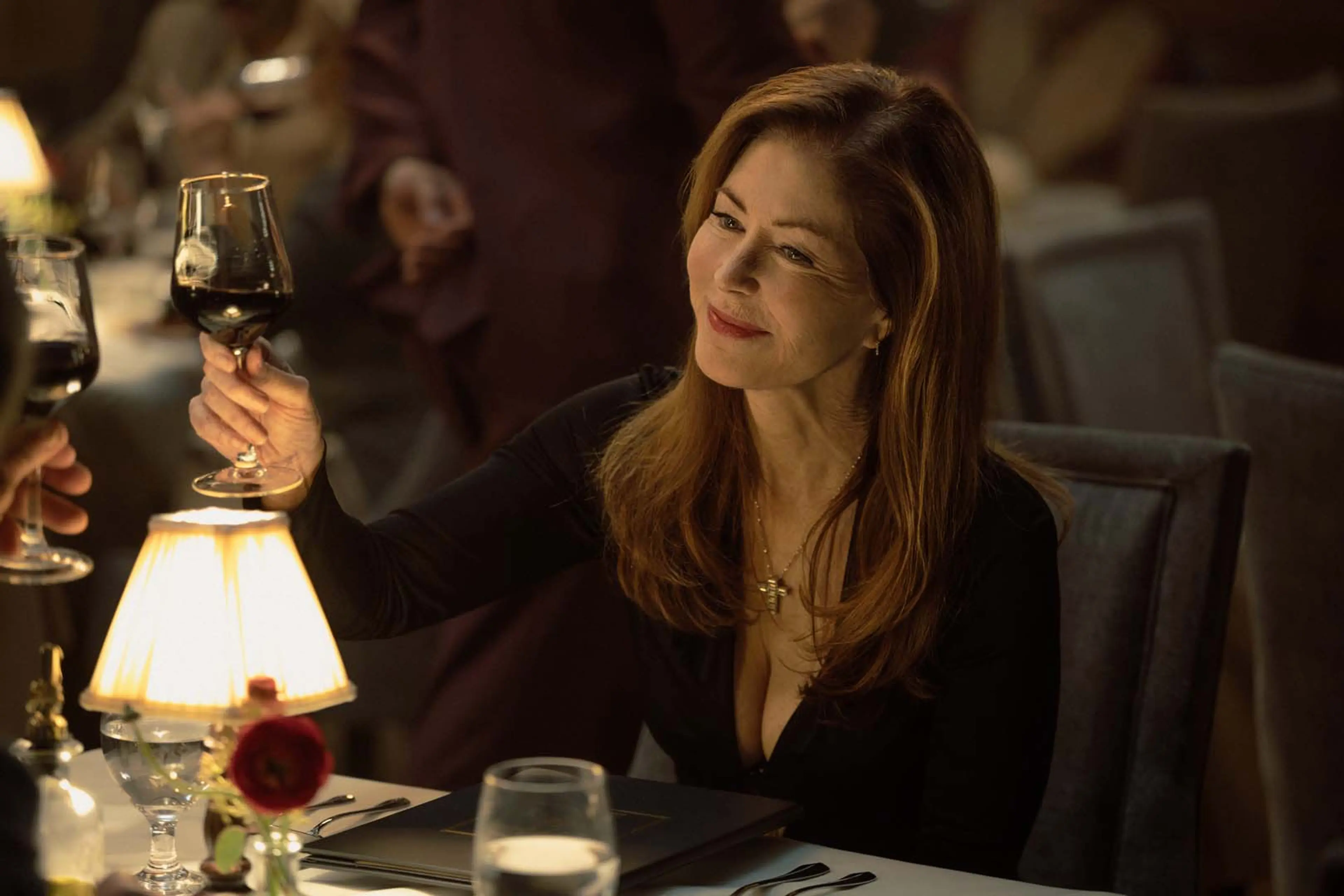 Dana Delany as Margaret raises a glass at a restaurant table in Tulsa King Season 4.