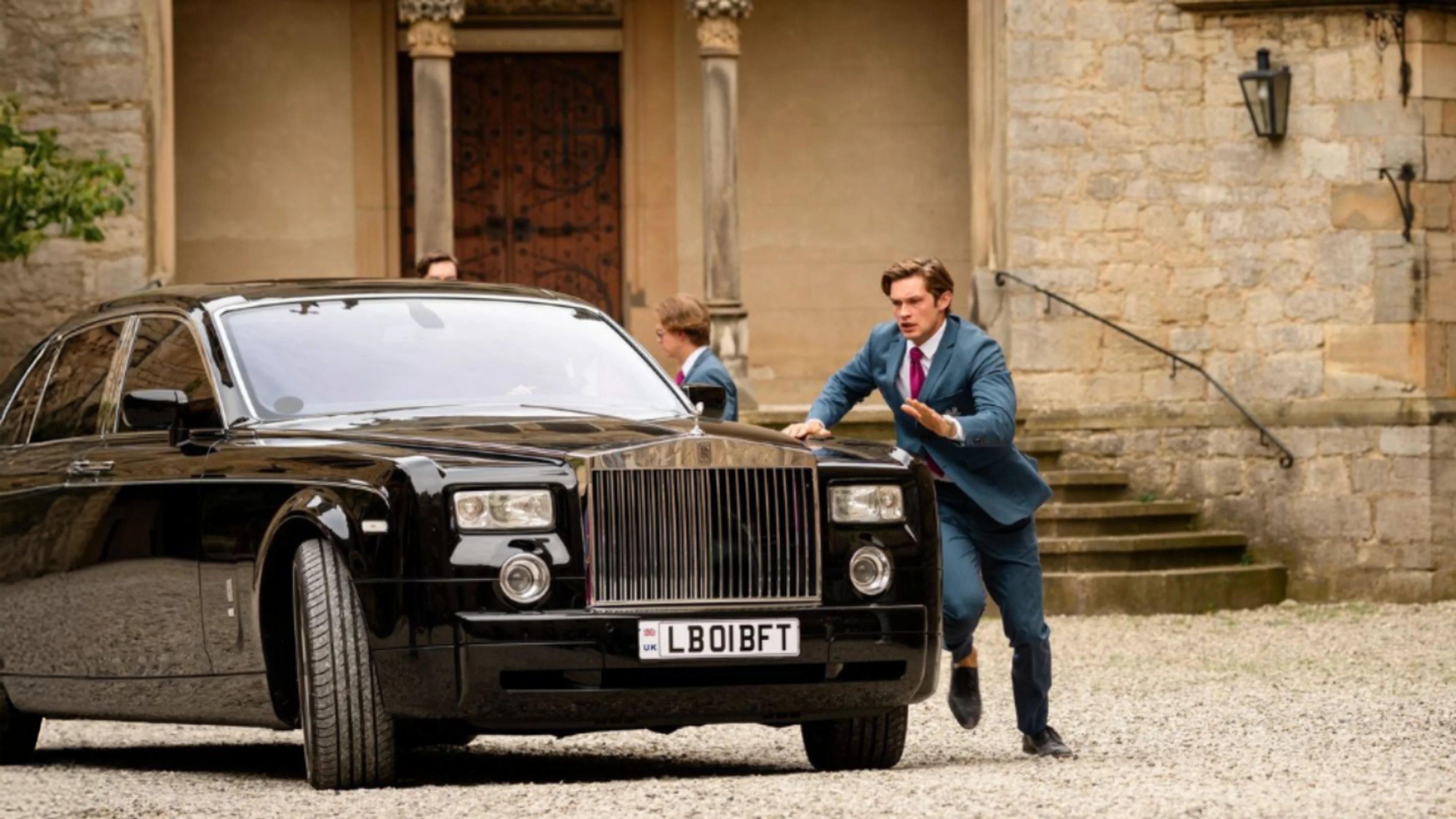 Damian Hardung as James Beaufort runs beside a black car outside Maxton Hall in a Season 3 still.