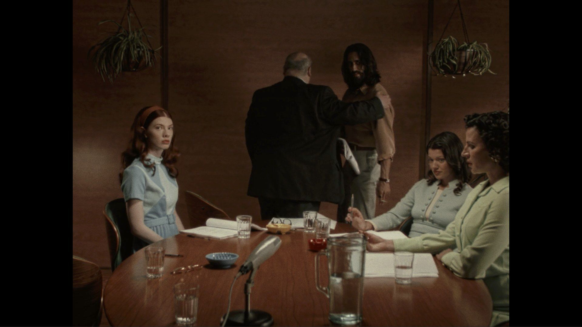 Marissa Marcel seated at a table during a film scene.