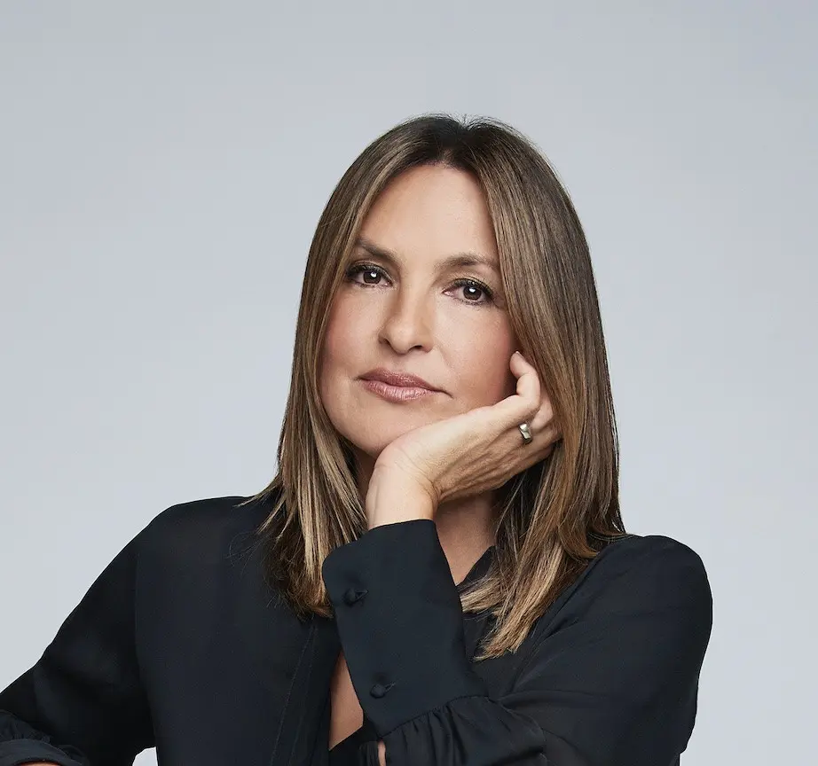 Mariska Hargitay looks toward the camera, resting her face on her hand in a black shirt.