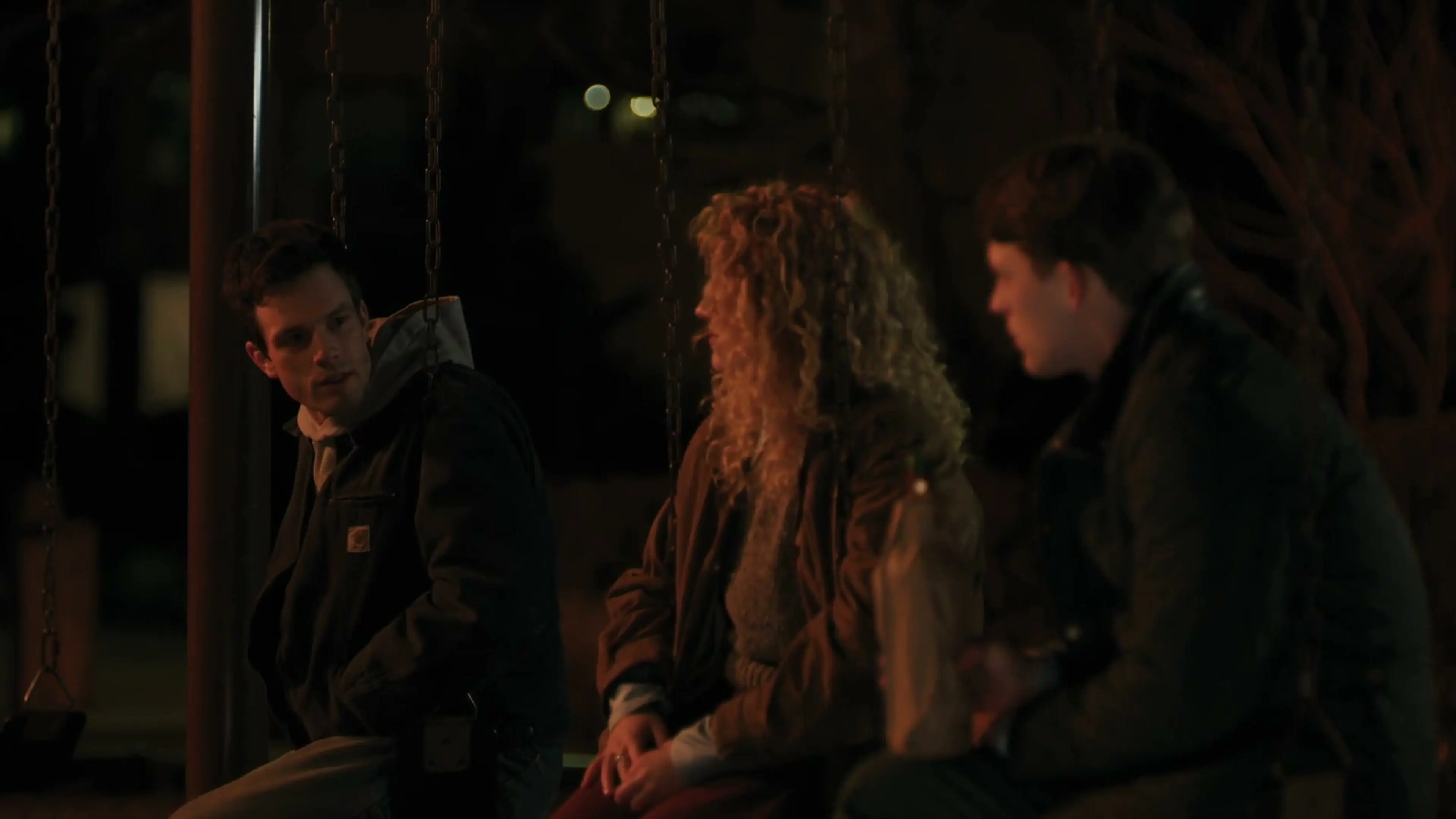 Three members of the Line of Fire family sit together outside at night.