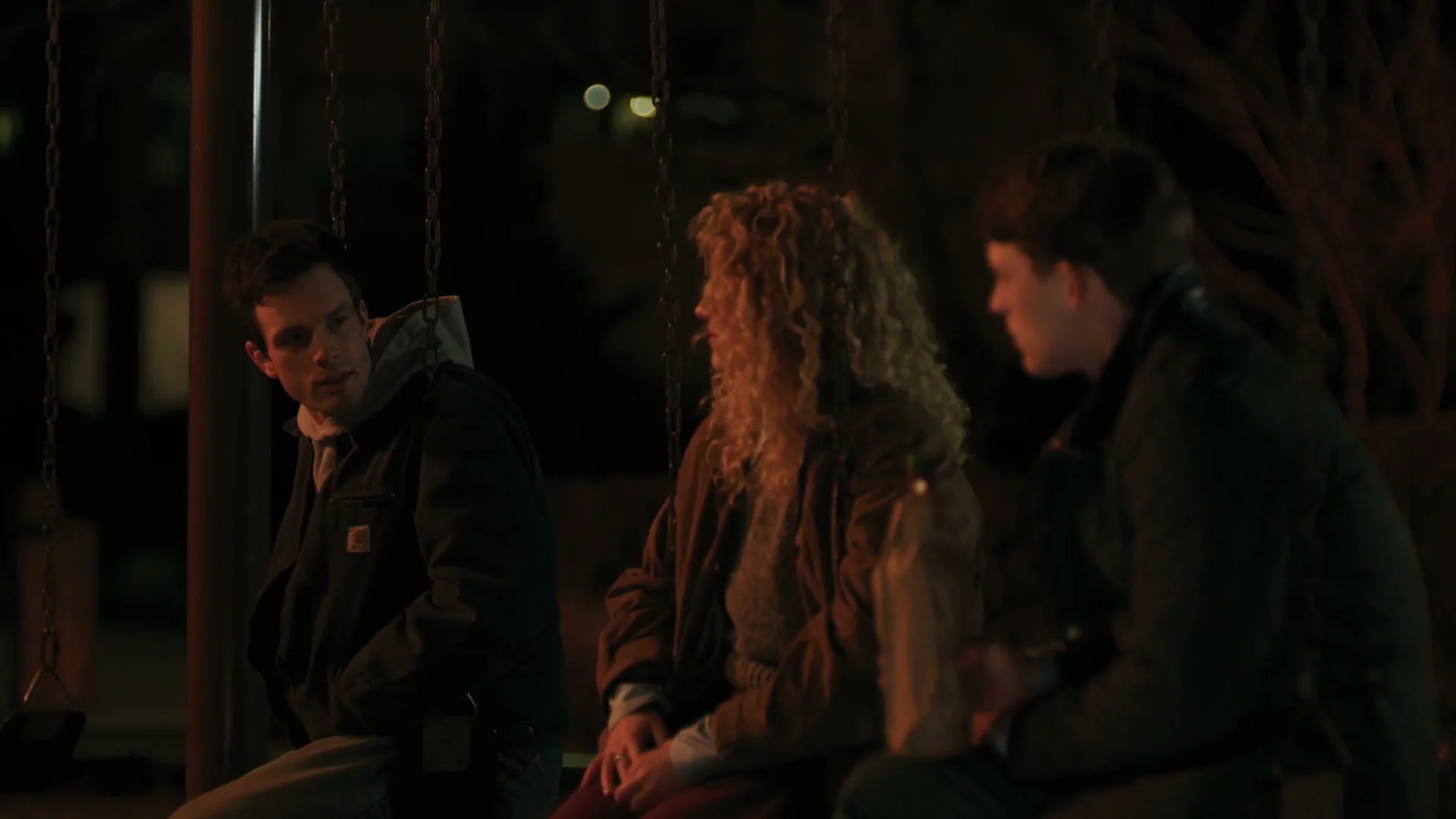 Three members of the Line of Fire family sit together outside at night.
