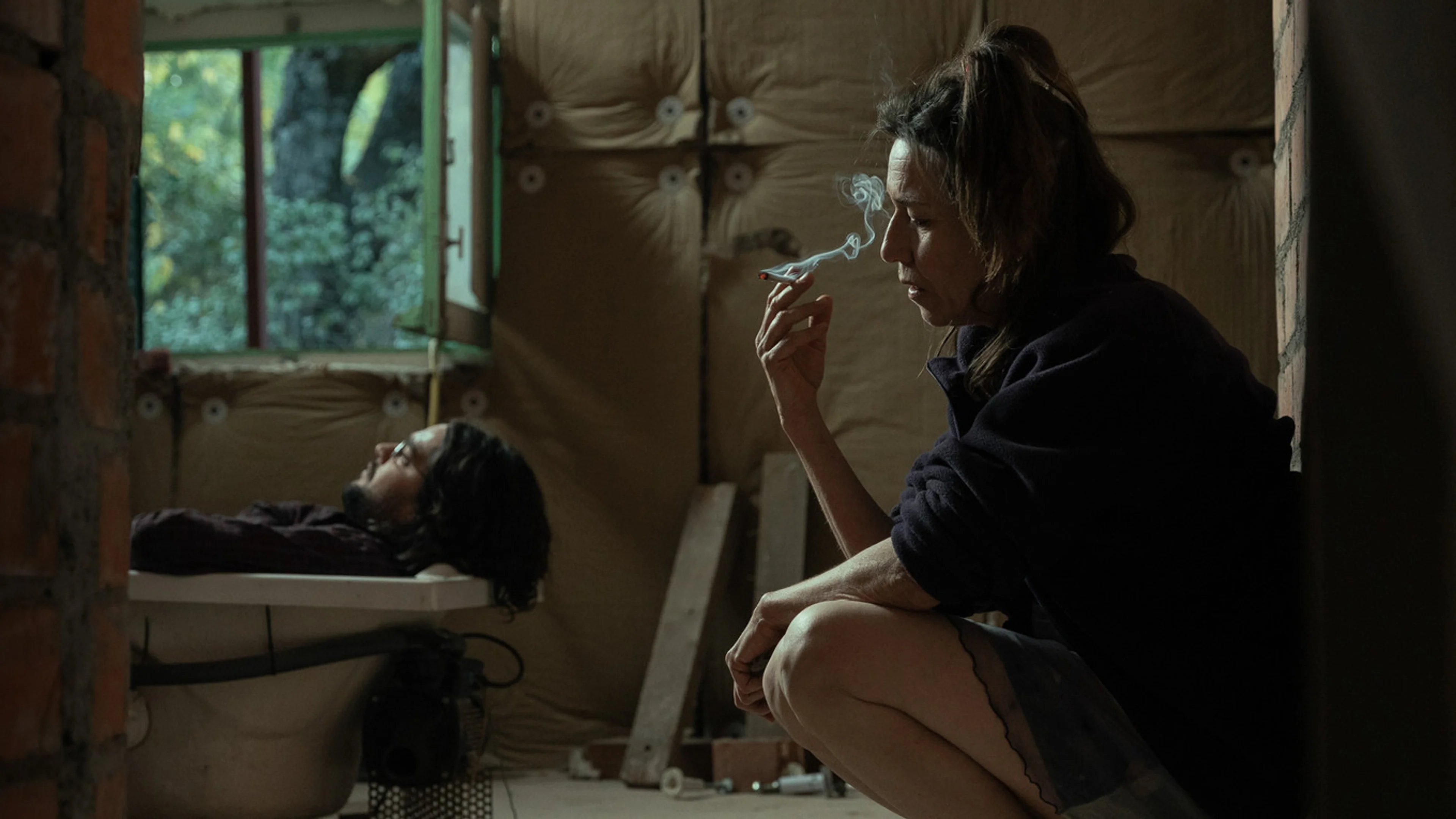 Lola Dueñas as Teresa sits smoking while Alberto lies behind her.