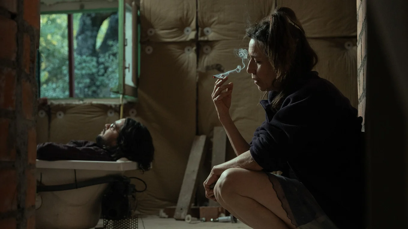 Lola Dueñas as Teresa sits smoking while Alberto lies behind her.