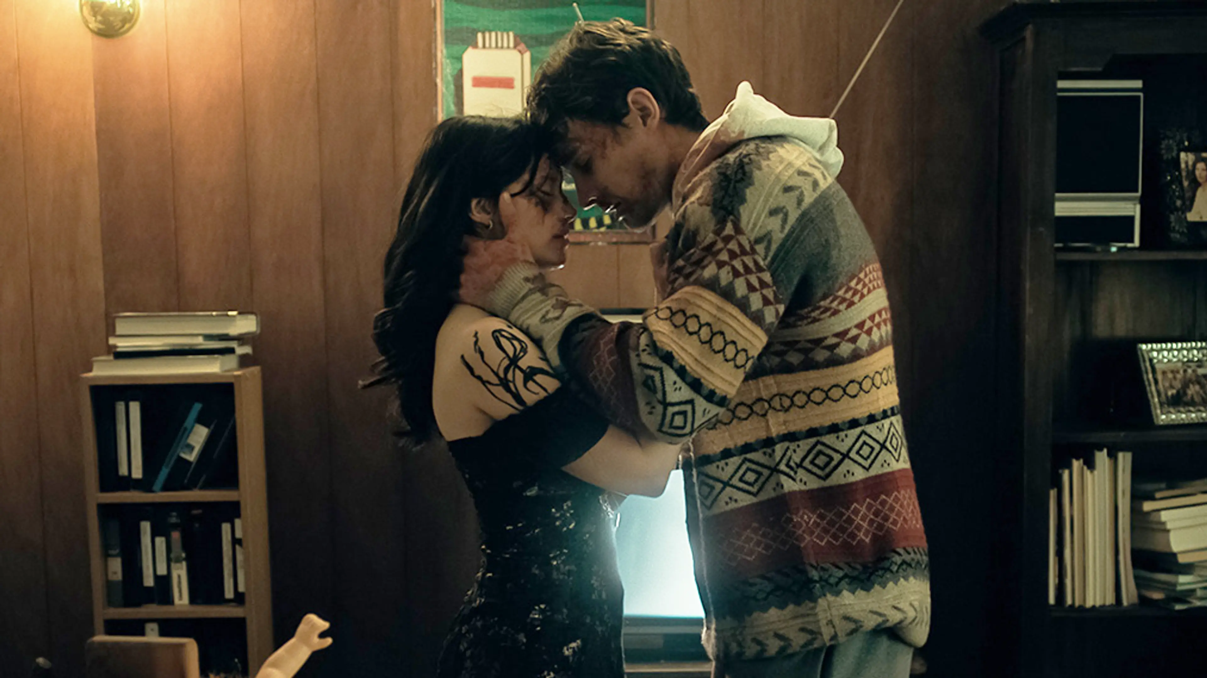 Bear and Nikki stand close together in a wood-paneled room.
