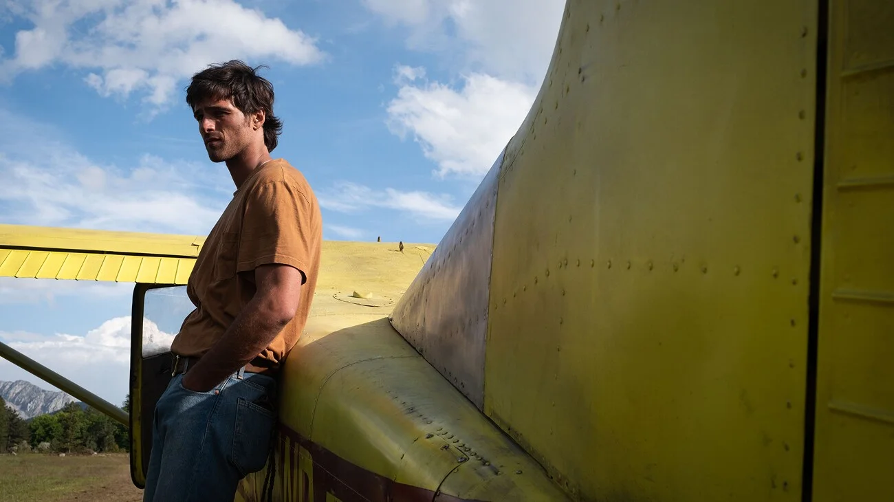 Jacob Elordi as Hig stands beside his yellow Cessna in The Dog Stars.