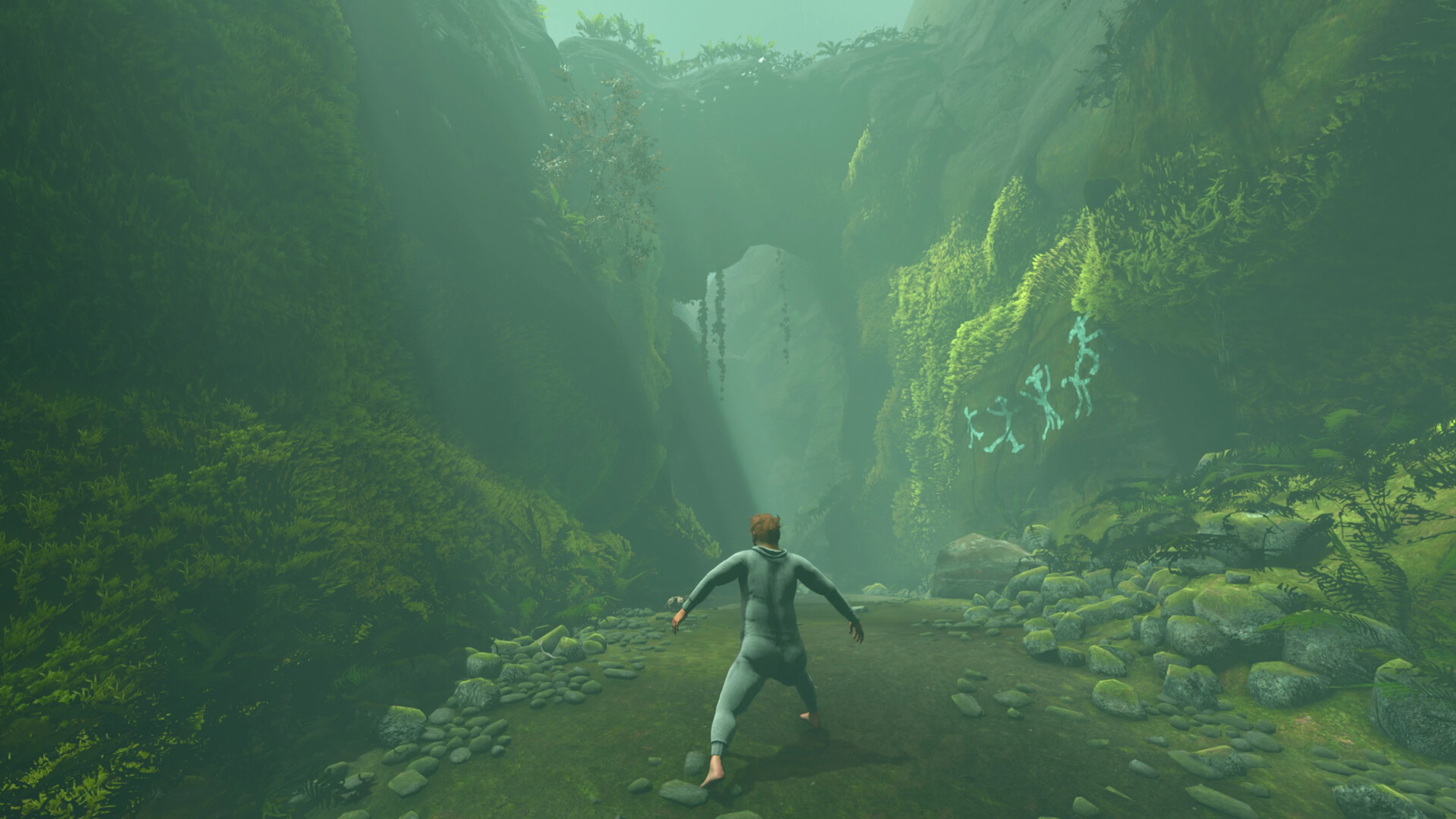 Nate takes a careful barefoot step into a moss-covered canyon in Baby Steps.