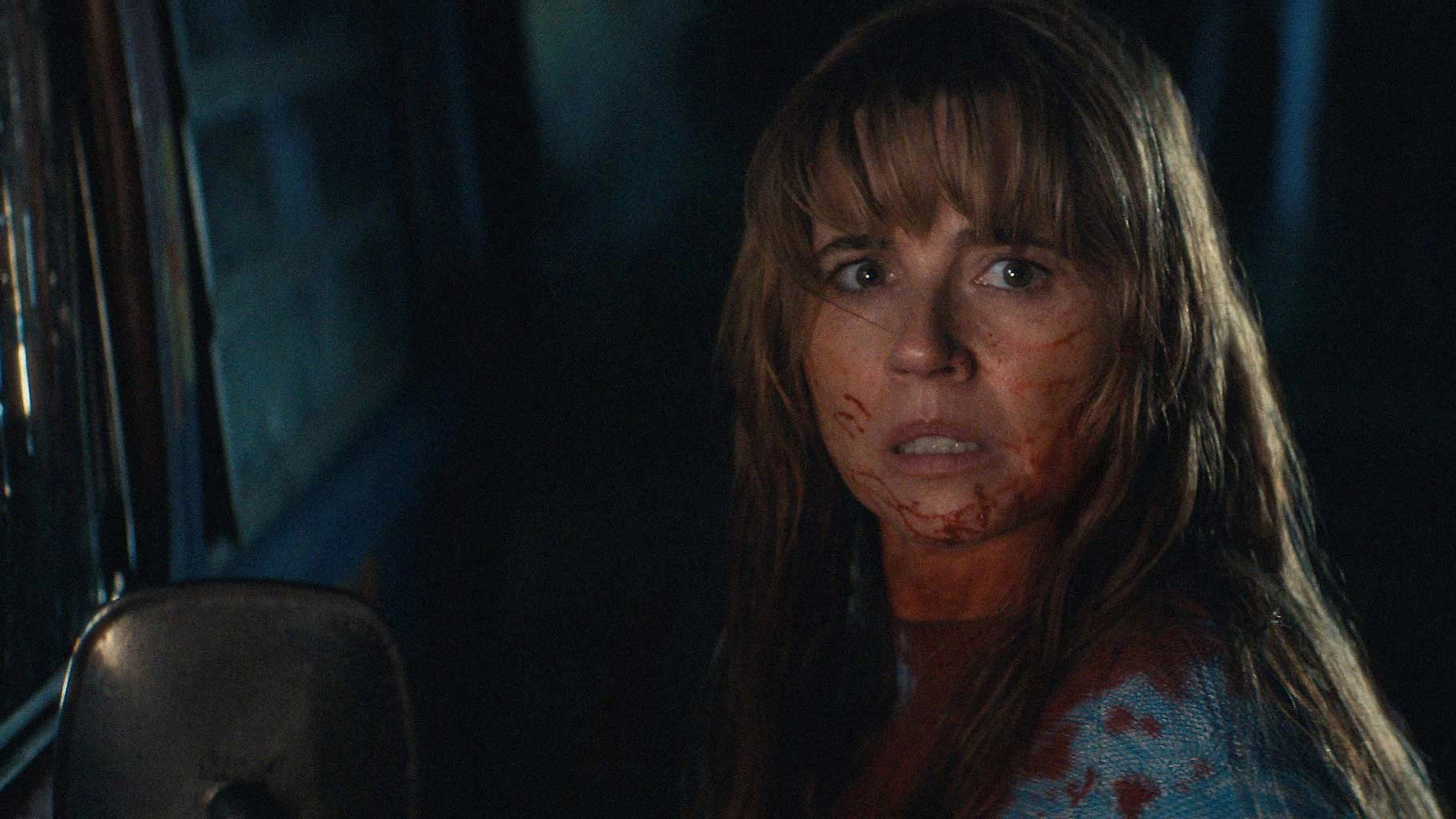 Linda Cardellini as Pamela Voorhees looks back from inside a car with blood on her face.