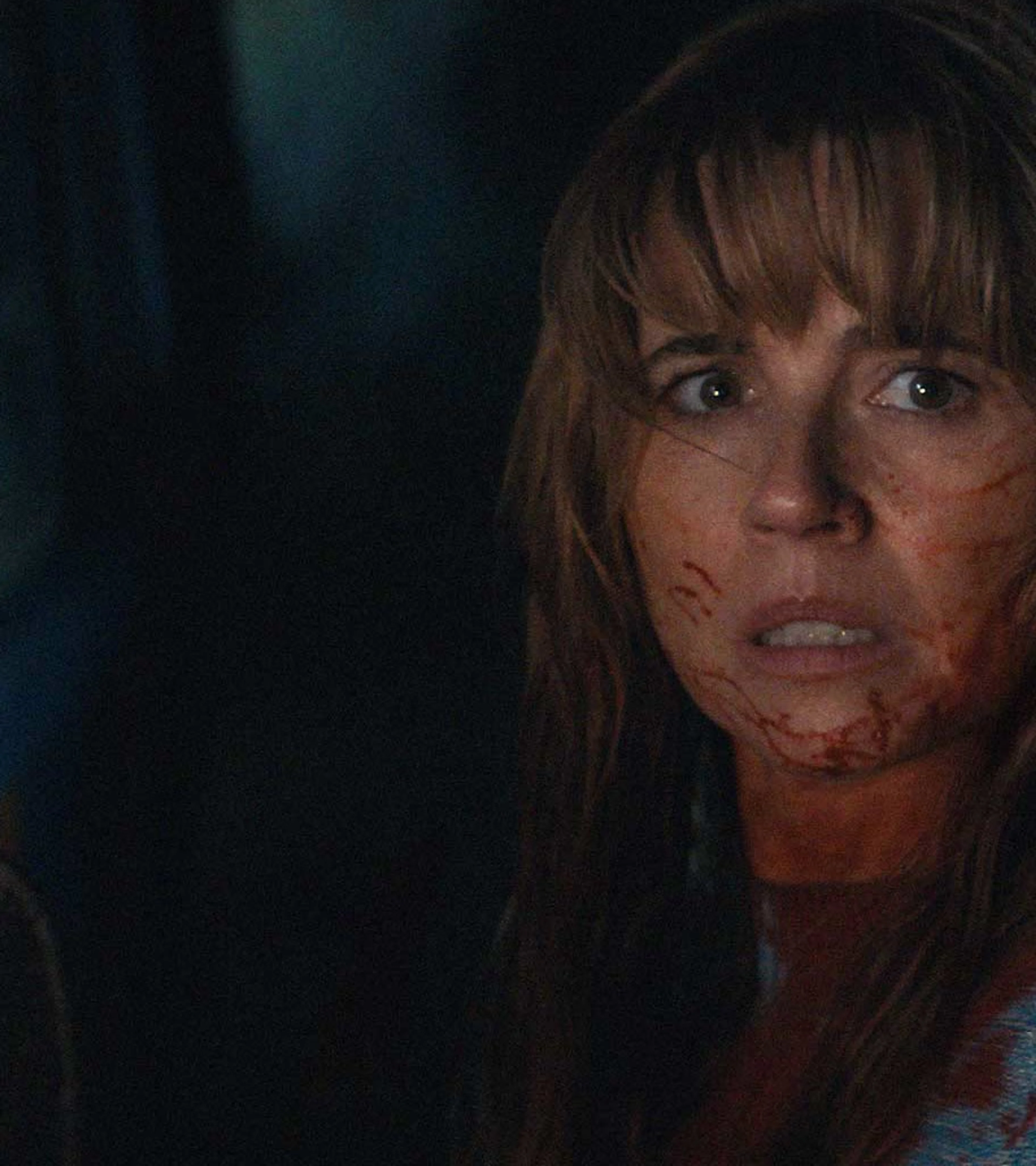 Linda Cardellini as Pamela Voorhees looks back from inside a car with blood on her face.