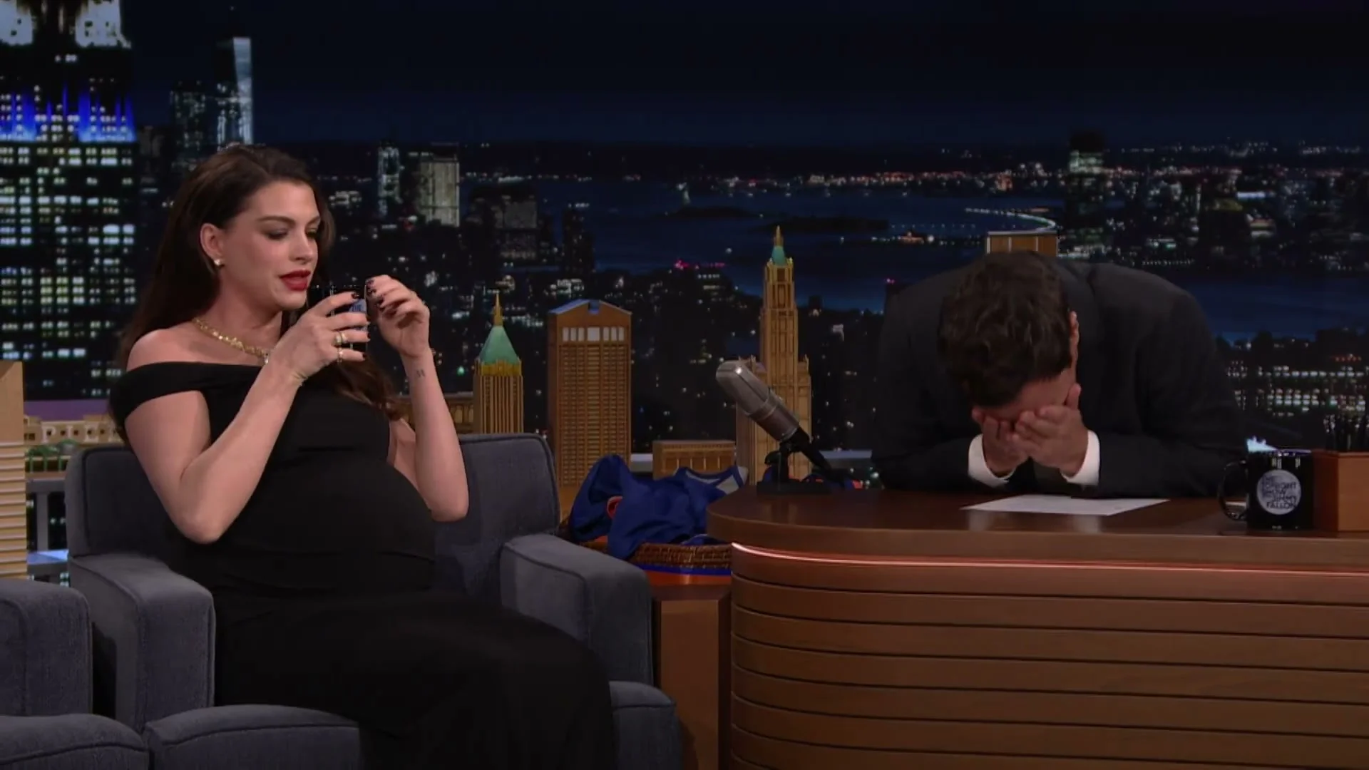 Anne Hathaway holds her coffee cup while Jimmy Fallon laughs during their Verity interview.