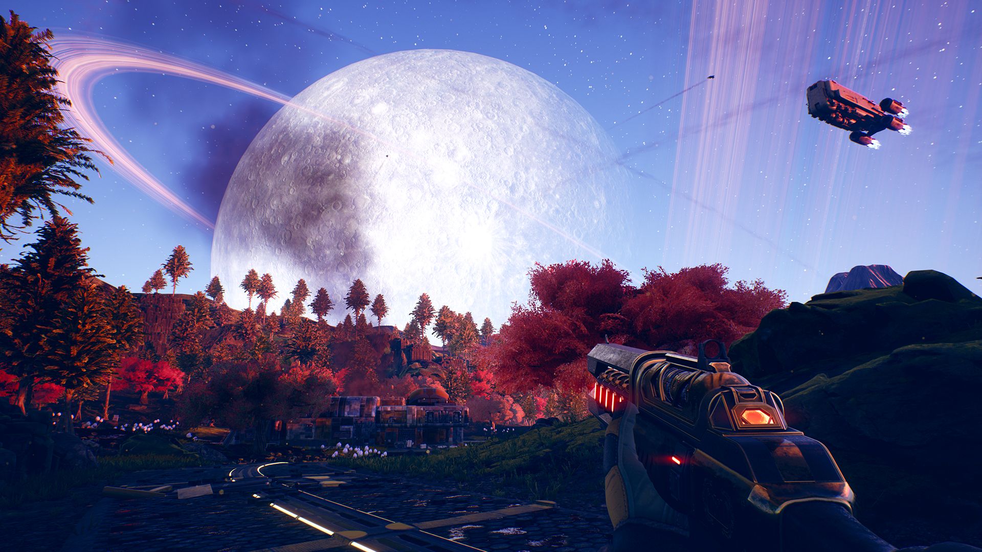 A ringed planet fills the sky above a pink and blue landscape in The Outer Worlds.
