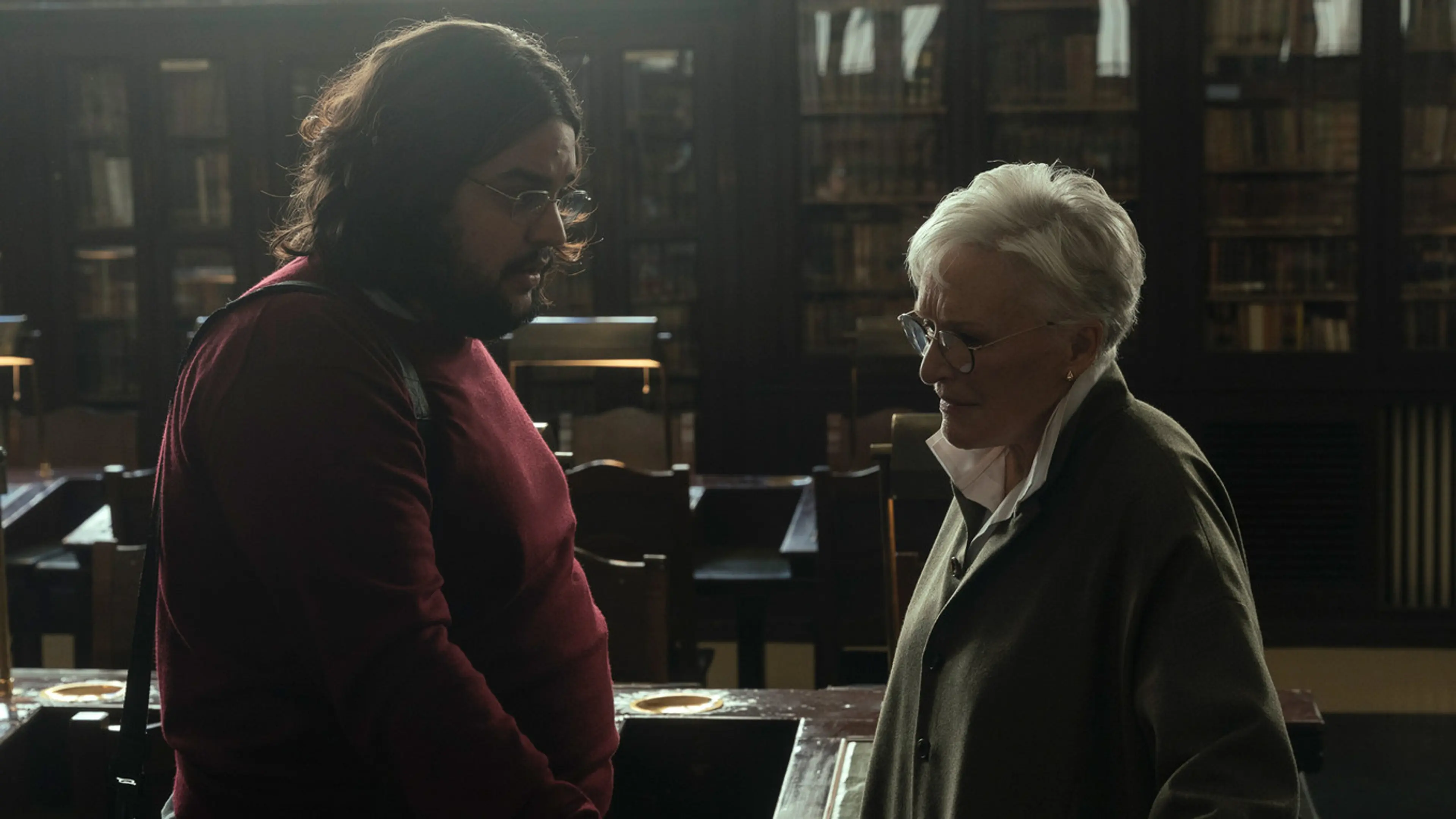 Carlos González as Alberto speaks with Glenn Close as Isabelle in a library.