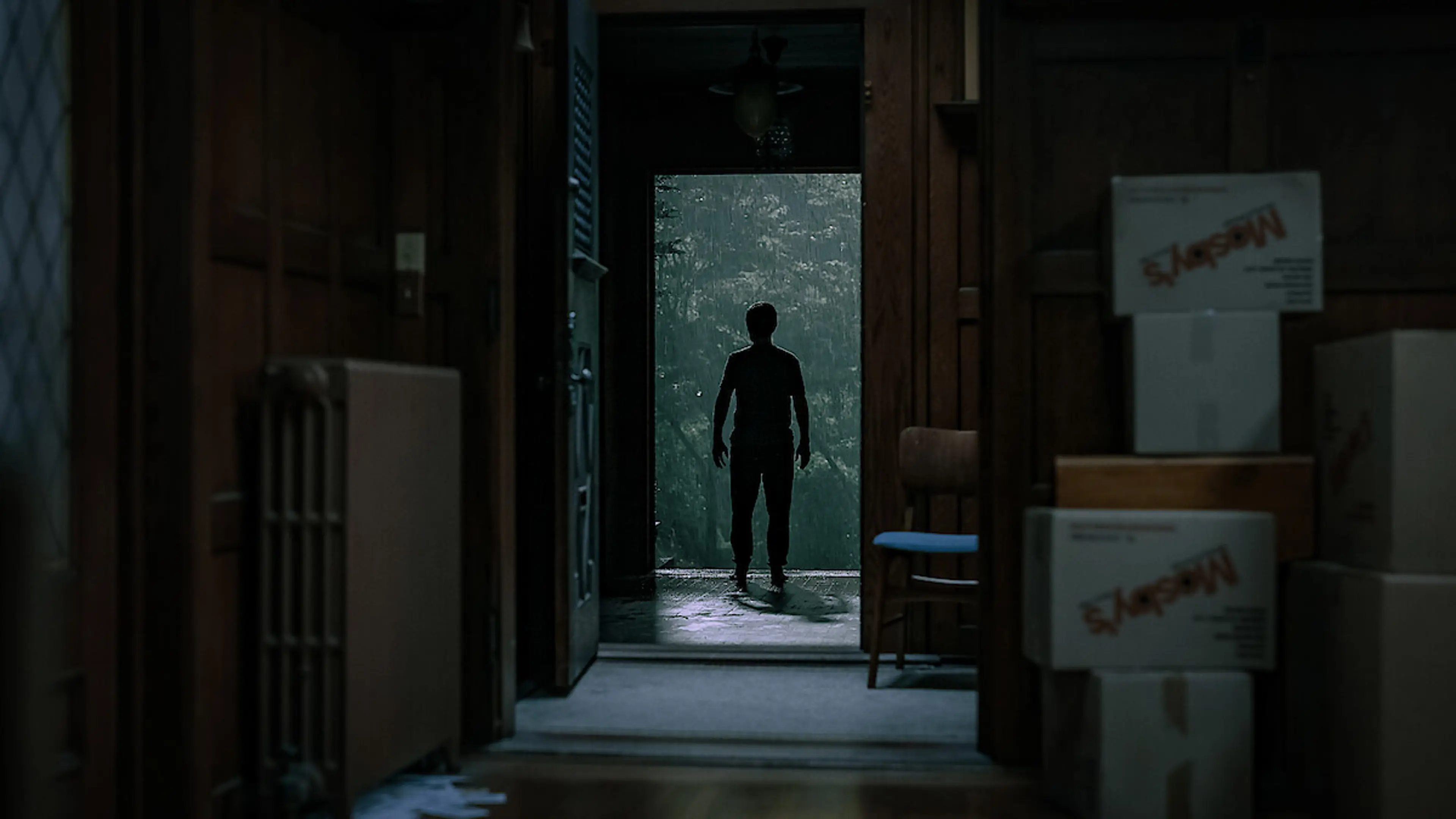 A silhouetted figure stands in the doorway of a house in The Whisper Man.