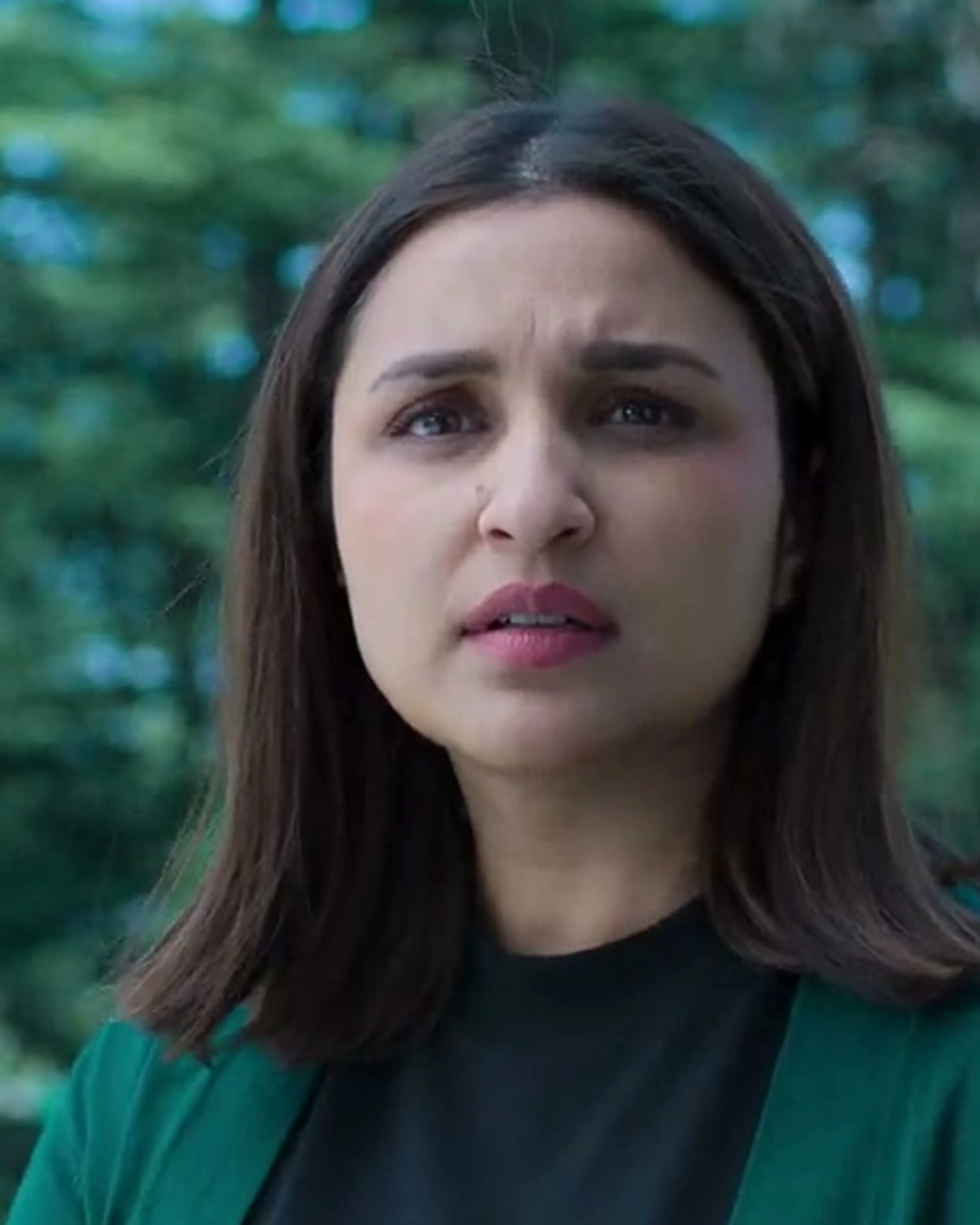 Parineeti Chopra as Anvita Dutt looks towards Rhea outside the school, wearing a dark green cardigan.