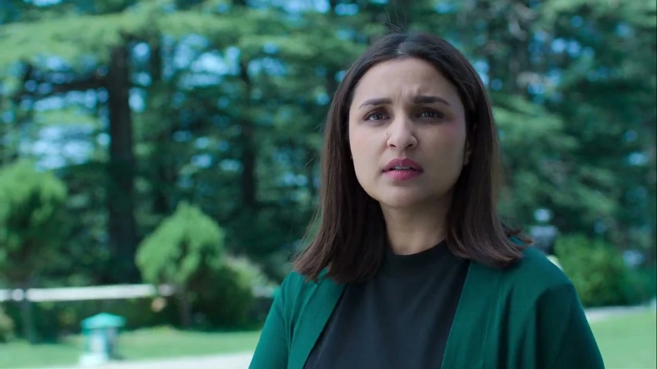 Parineeti Chopra as Anvita Dutt looks towards Rhea outside the school, wearing a dark green cardigan.