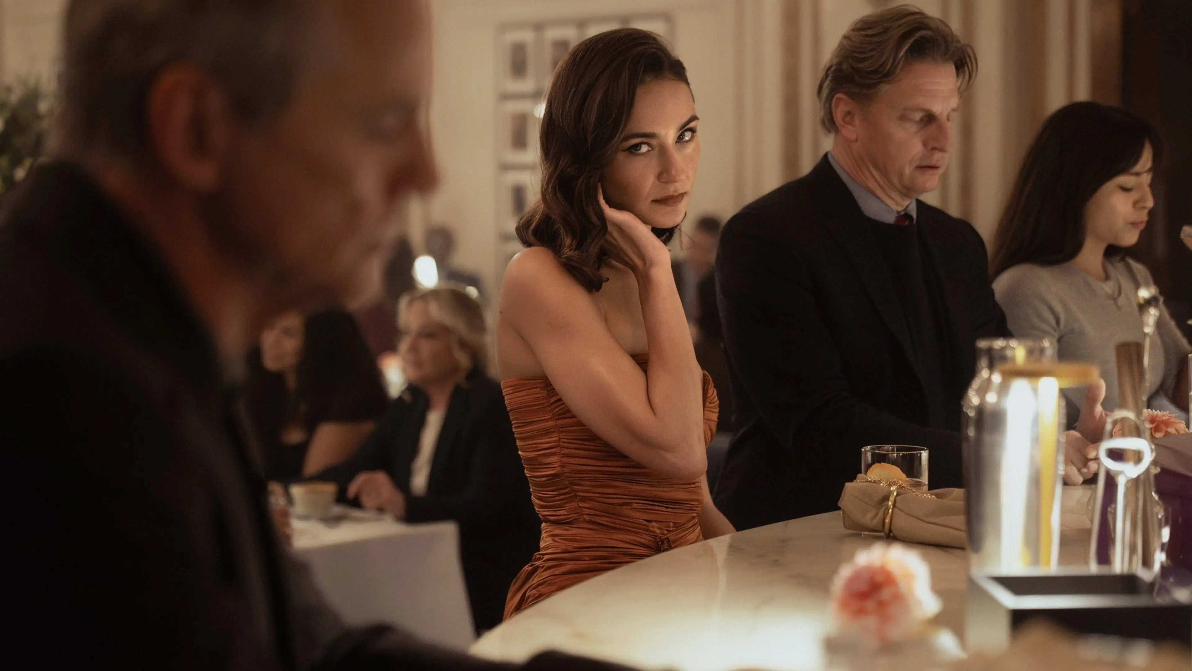 A young woman looks across a crowded family gathering in Lioness Season 3.