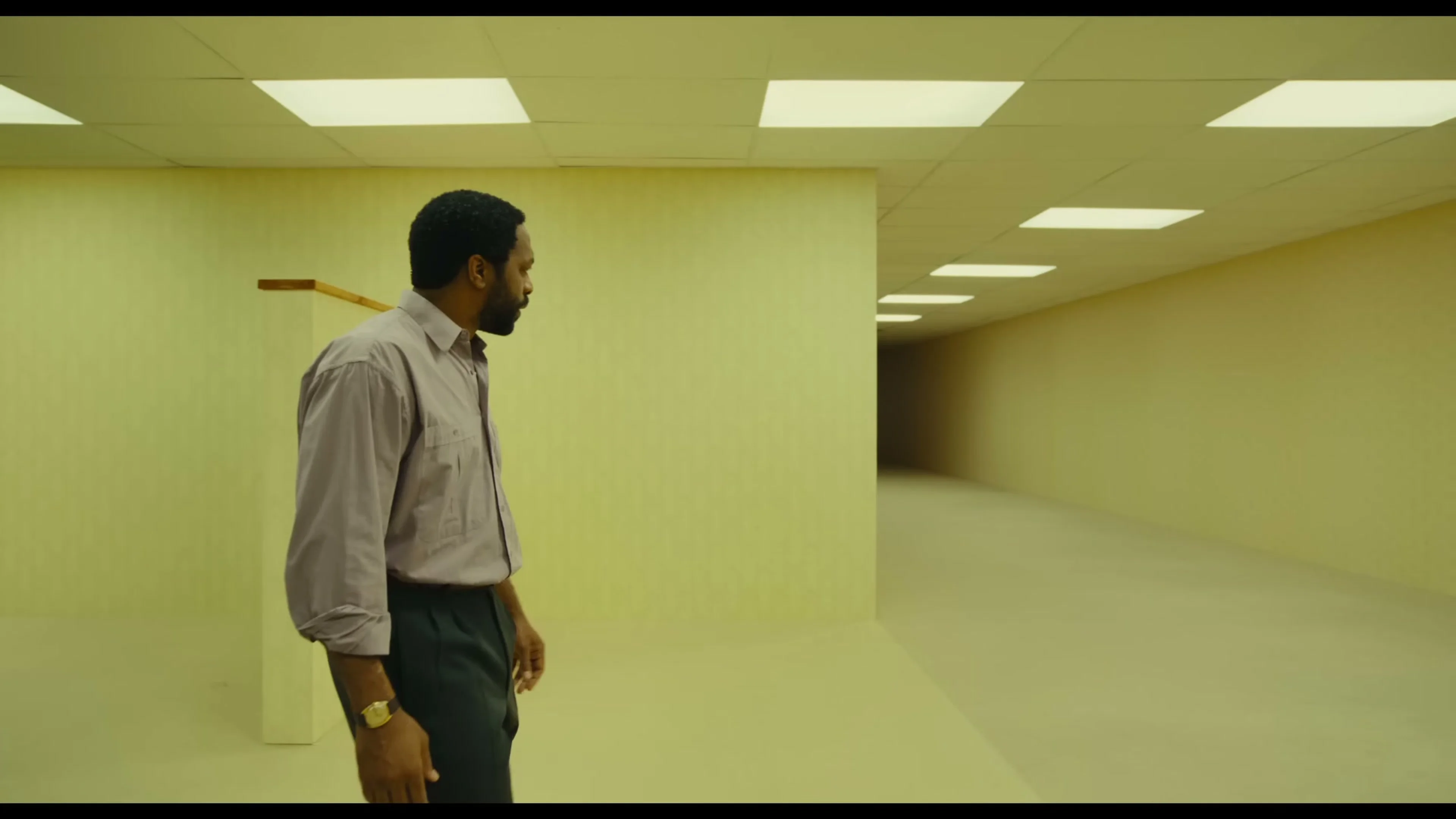 Clark looks down a long yellow corridor beneath fluorescent ceiling lights.