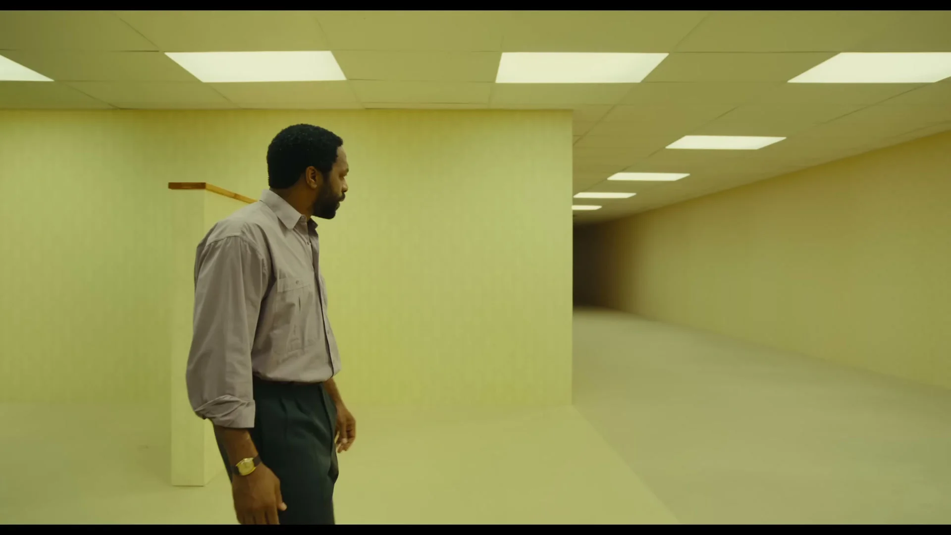 Clark looks down a long yellow corridor beneath fluorescent ceiling lights.