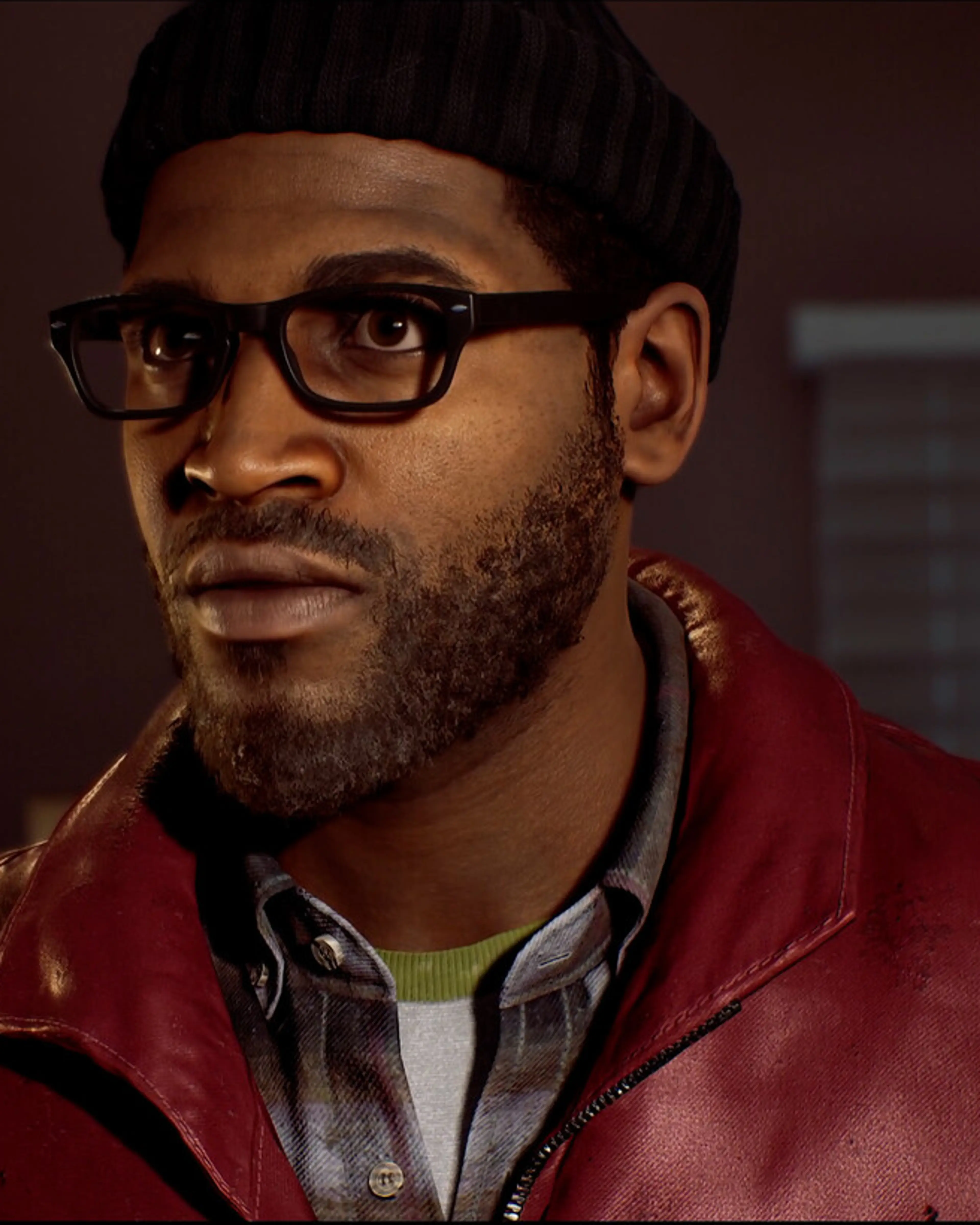 Simon Ordell looks towards someone in an indoor room while wearing glasses and a hat.